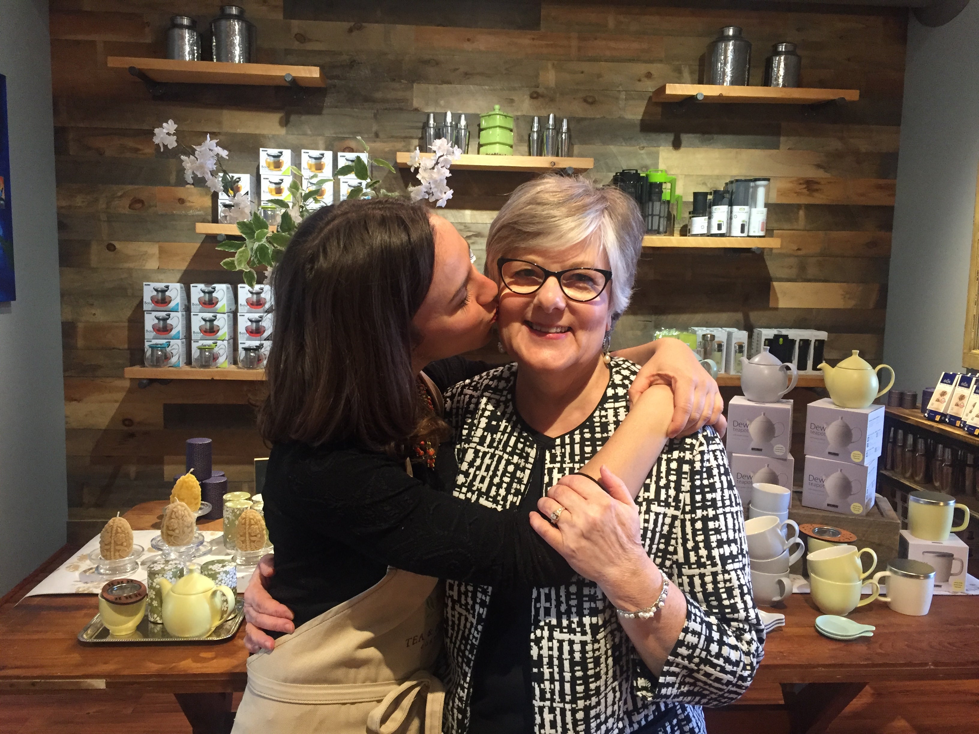 woman kissing her mom in front of teaware and gifts