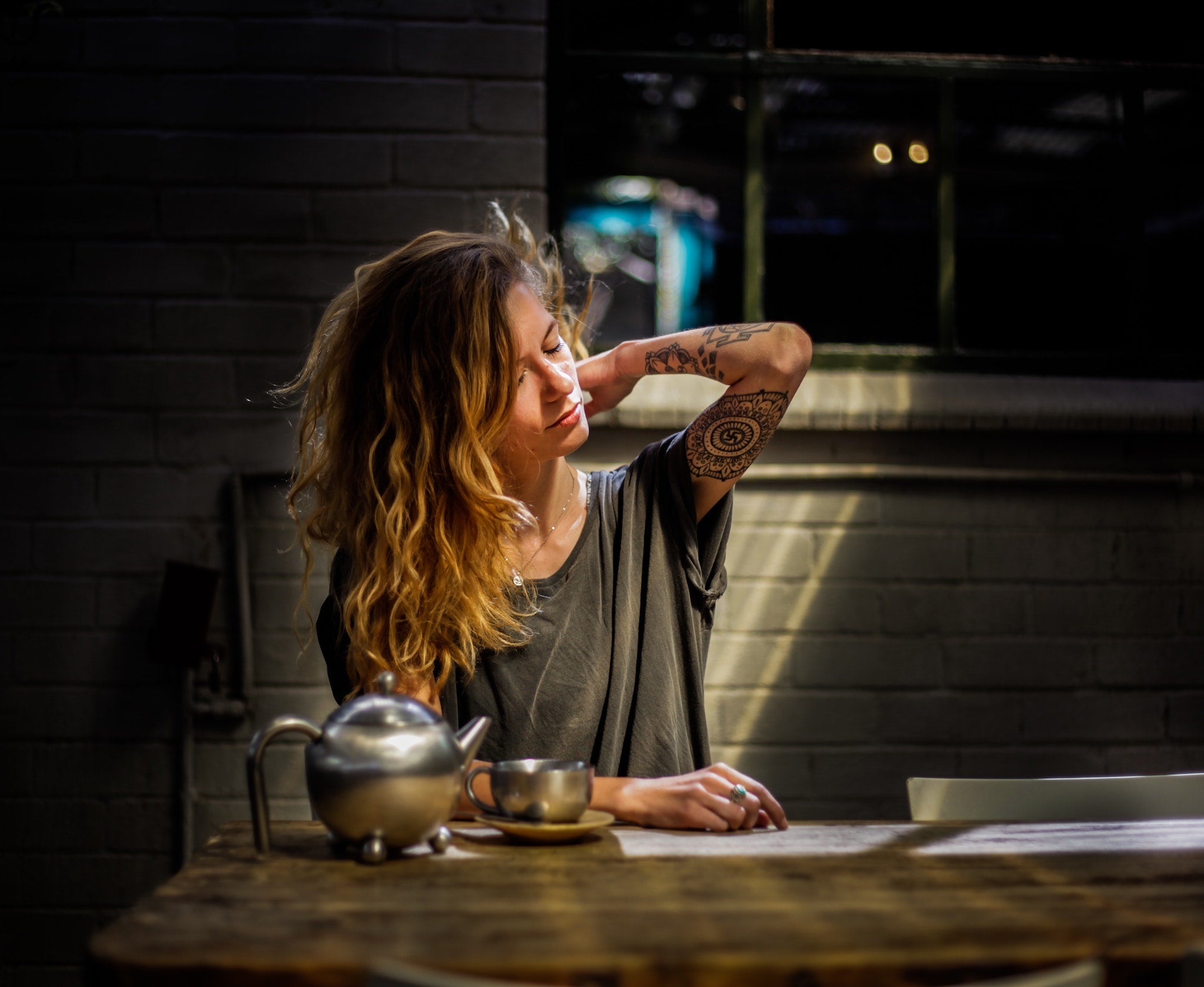 woman with tea for pain relief exhibiting signs of muscle aches and pains by rubbing her neck