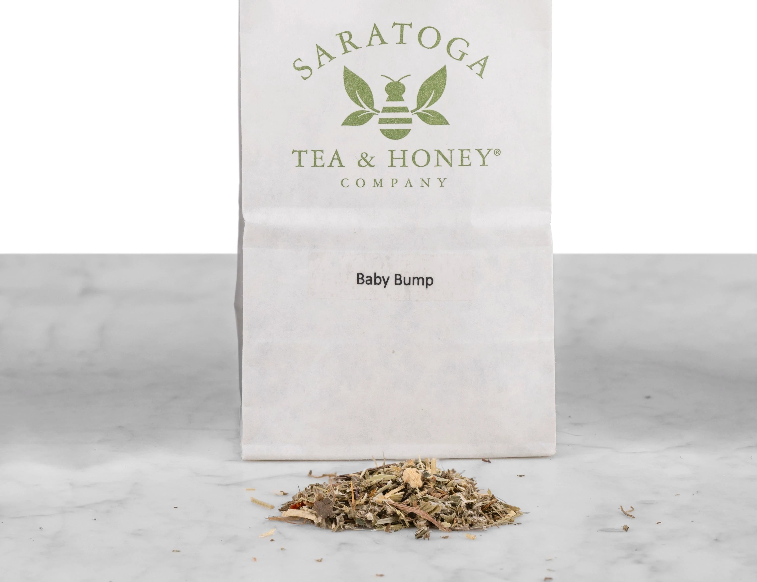 Close up of Baby Bump pregnancy red raspberry leaf tea. The tea is in a pile in front of a white Saratoga Tea & Honey Co tea bag.