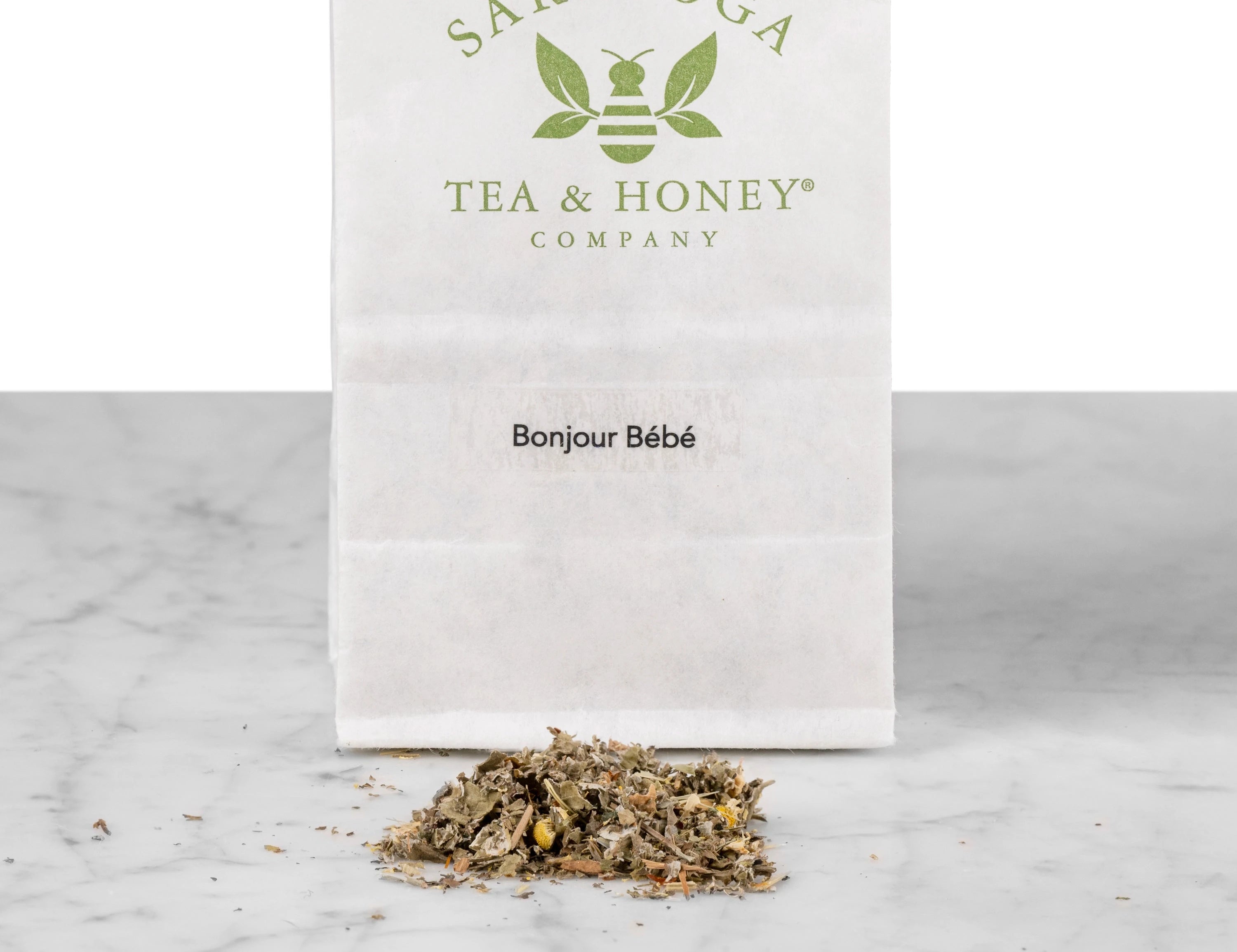 Close up of Bonjour Bébé post-partum oat straw and chamomile tea. The tea is in a pile in front of a white Saratoga Tea & Honey Co tea bag.