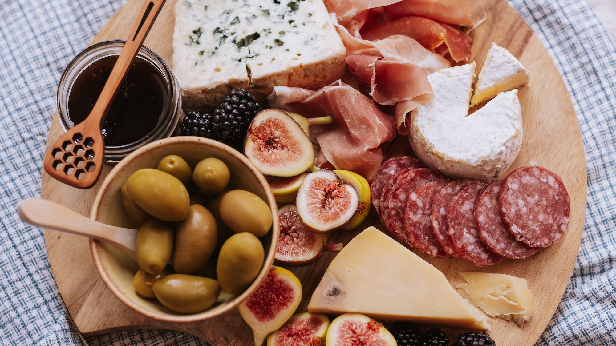 charcuterie board with dark honey, figs, olives, salami and cheese