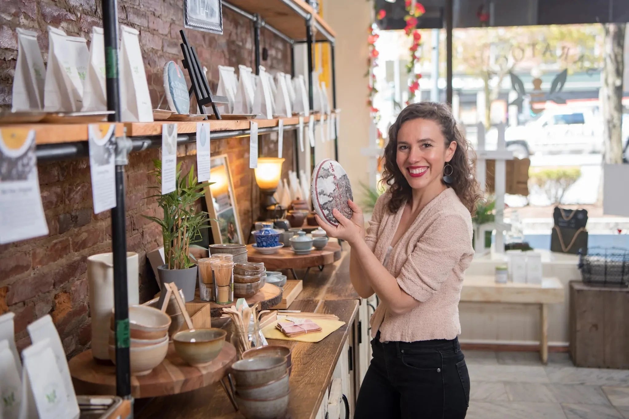 Saratoga Tea & Honey Co. founder Hayley Stevens showcasing a rare pu erh tea cake in her flagship tea store in Saratoga Springs, NY