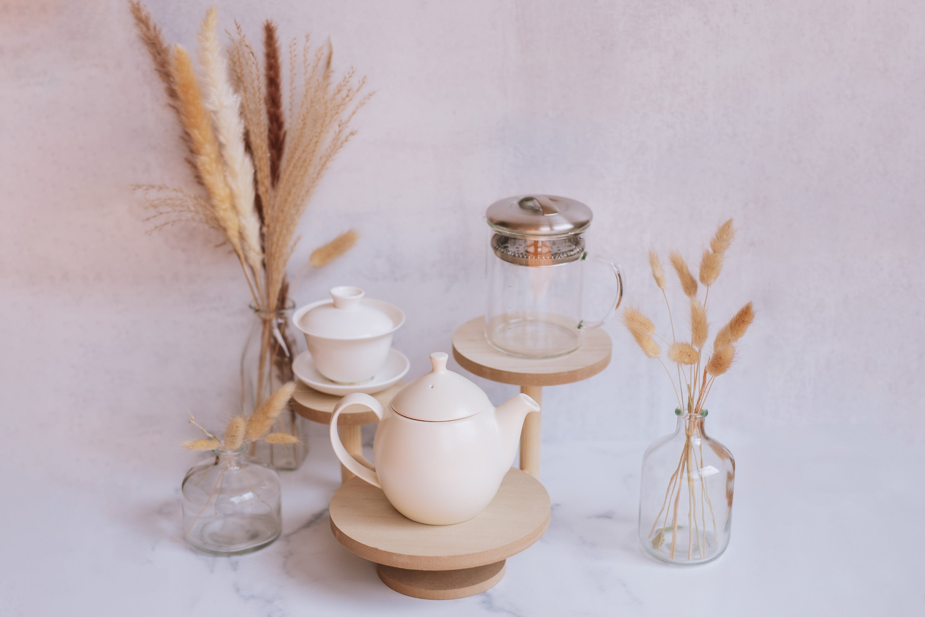 traditional and western teaware displayed on wooden stands against neutral grey background