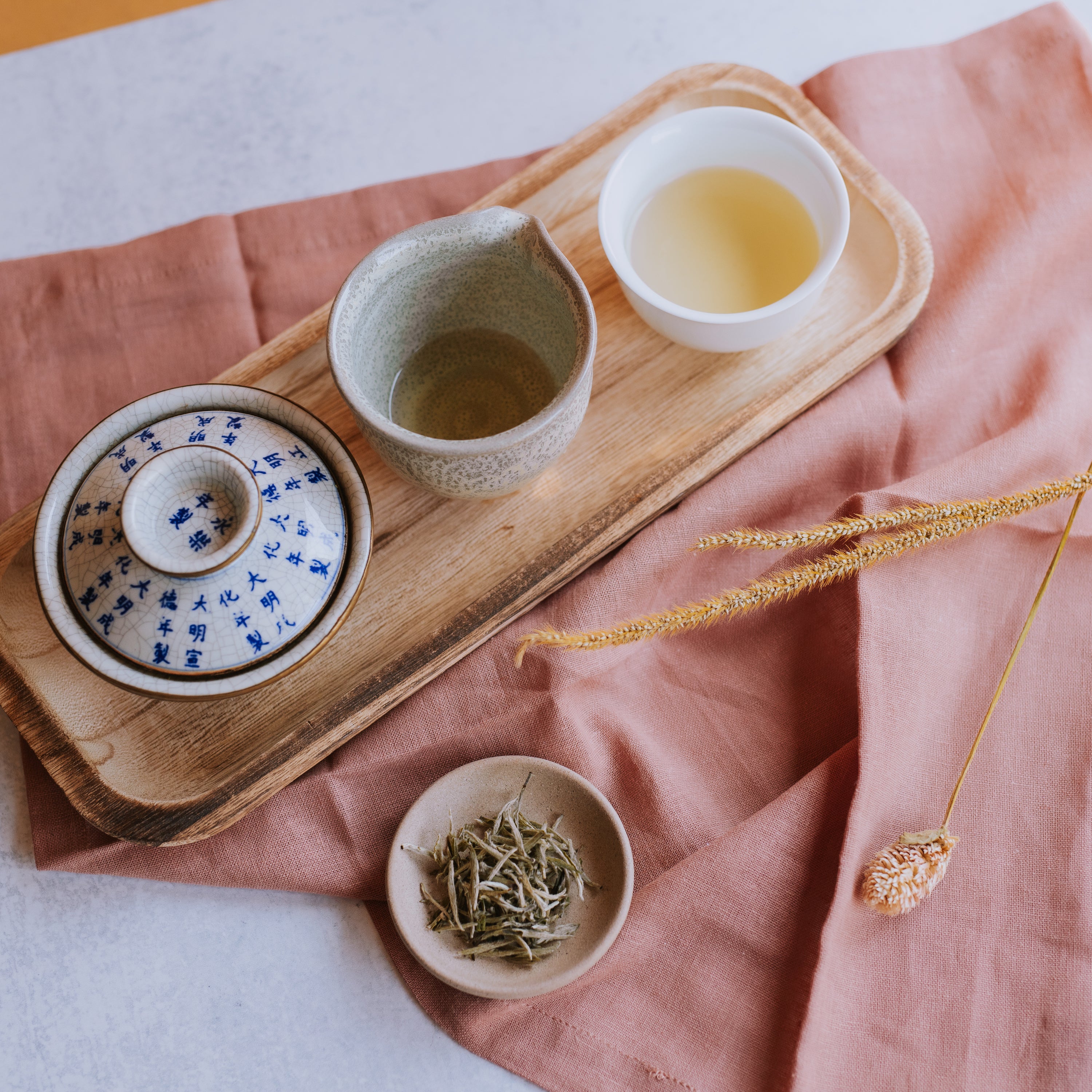 gaiwan with pitcher and cup of white tea and small dish of loose leaf silver needle white tea