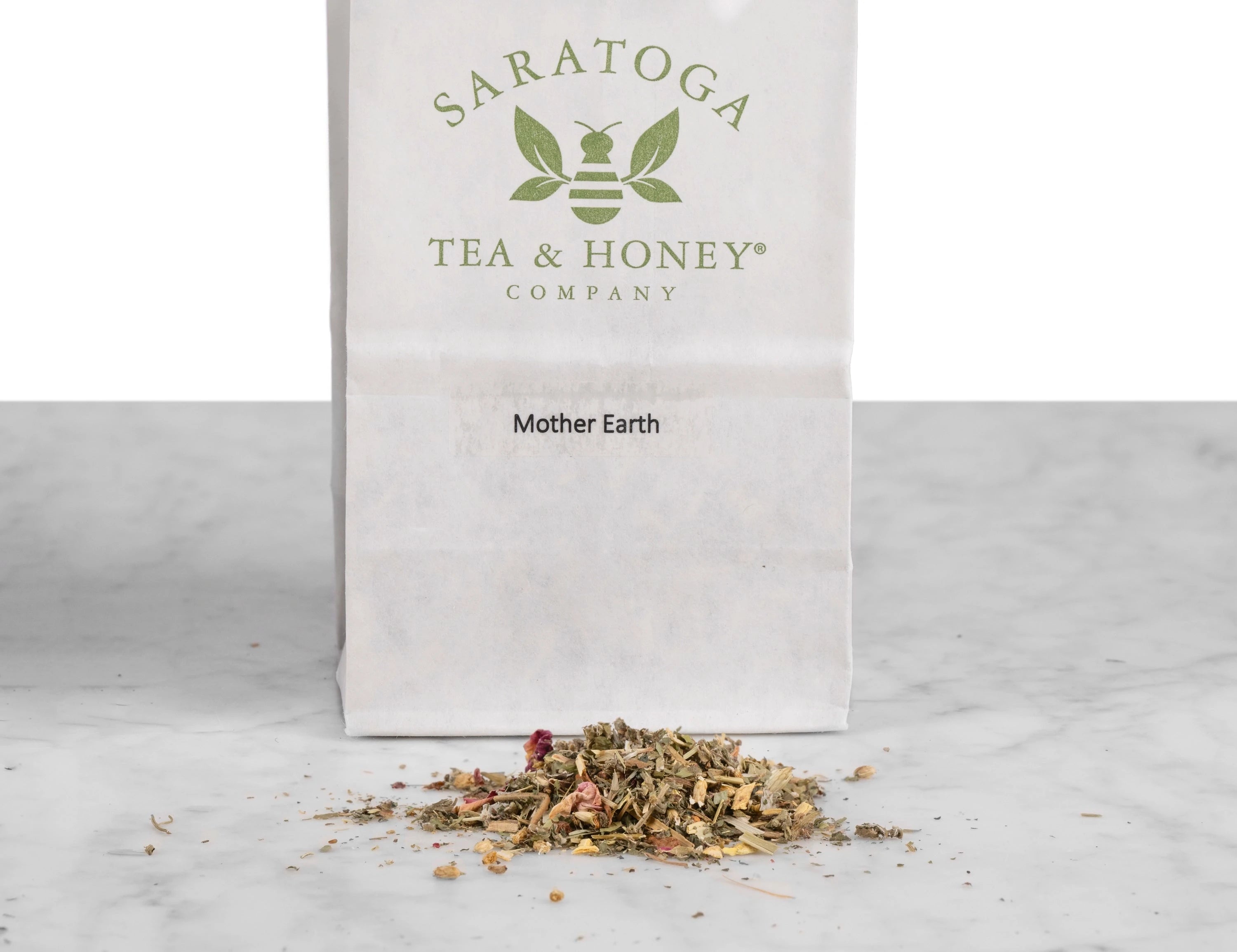 Close up of Mother Earth fertility tea. The tea is in a pile in front of a white Saratoga Tea & Honey Co tea bag.