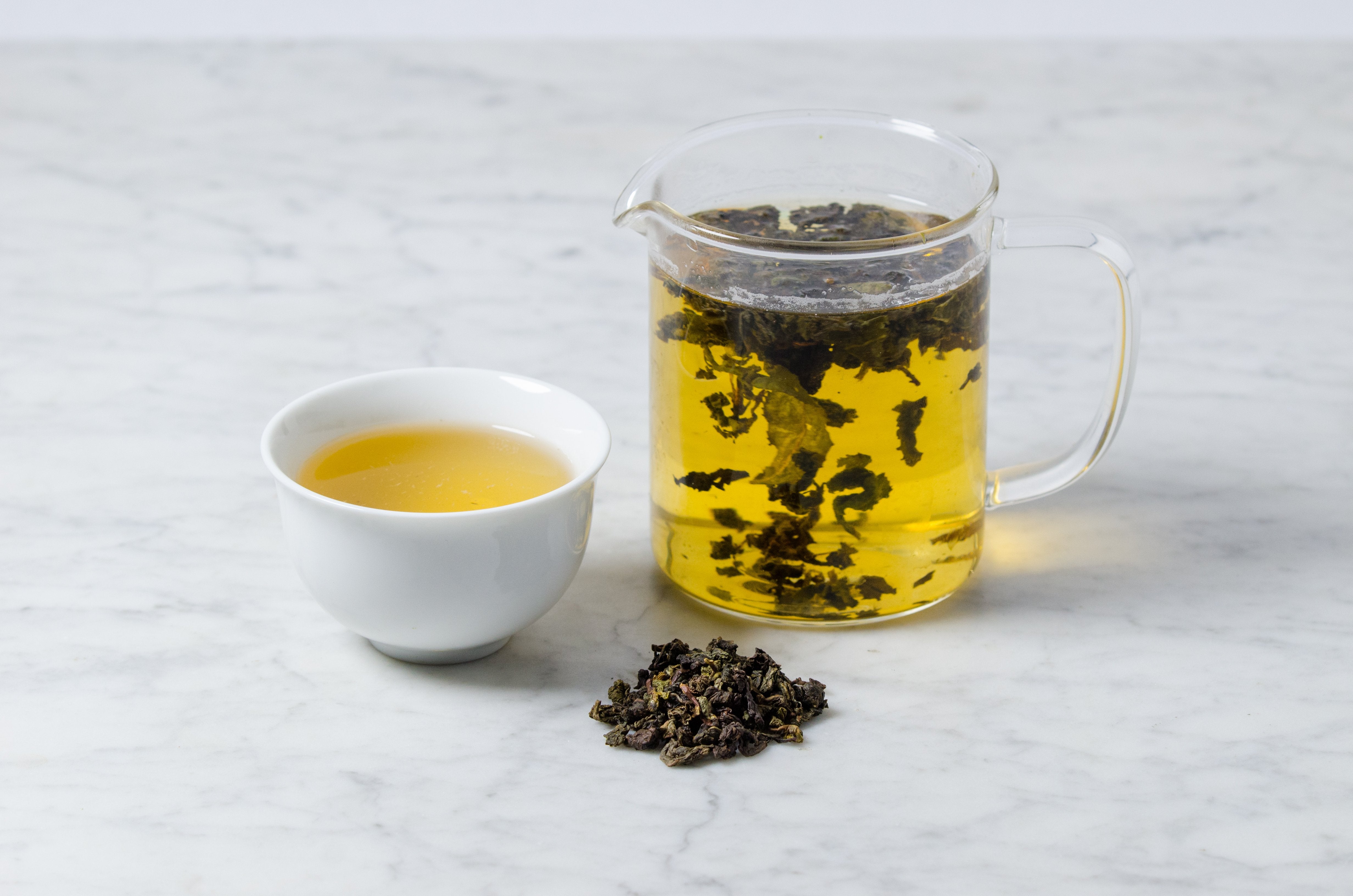 steeped oolong loose leaf tea in a glass infuser and white cup