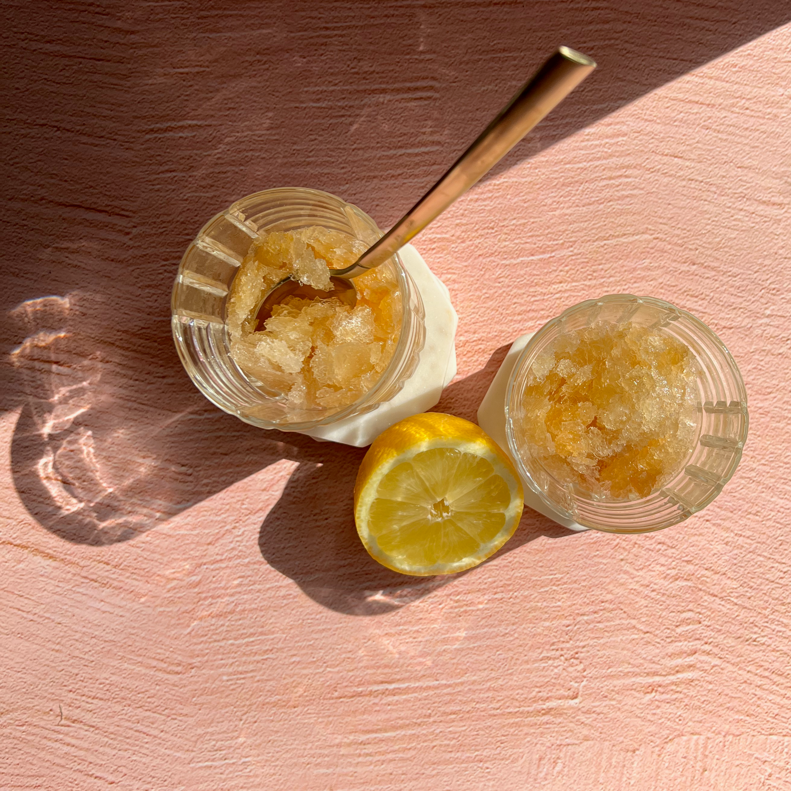 slushy iced tea lemonade cocktail in rocks glass with spoon and lemon half