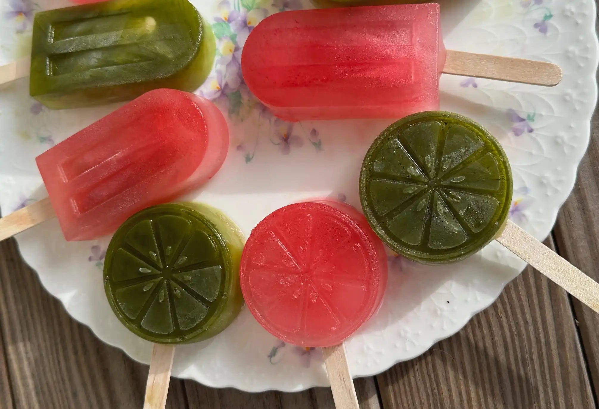 bright green and pink iced tea lemonade popsicles on a plate