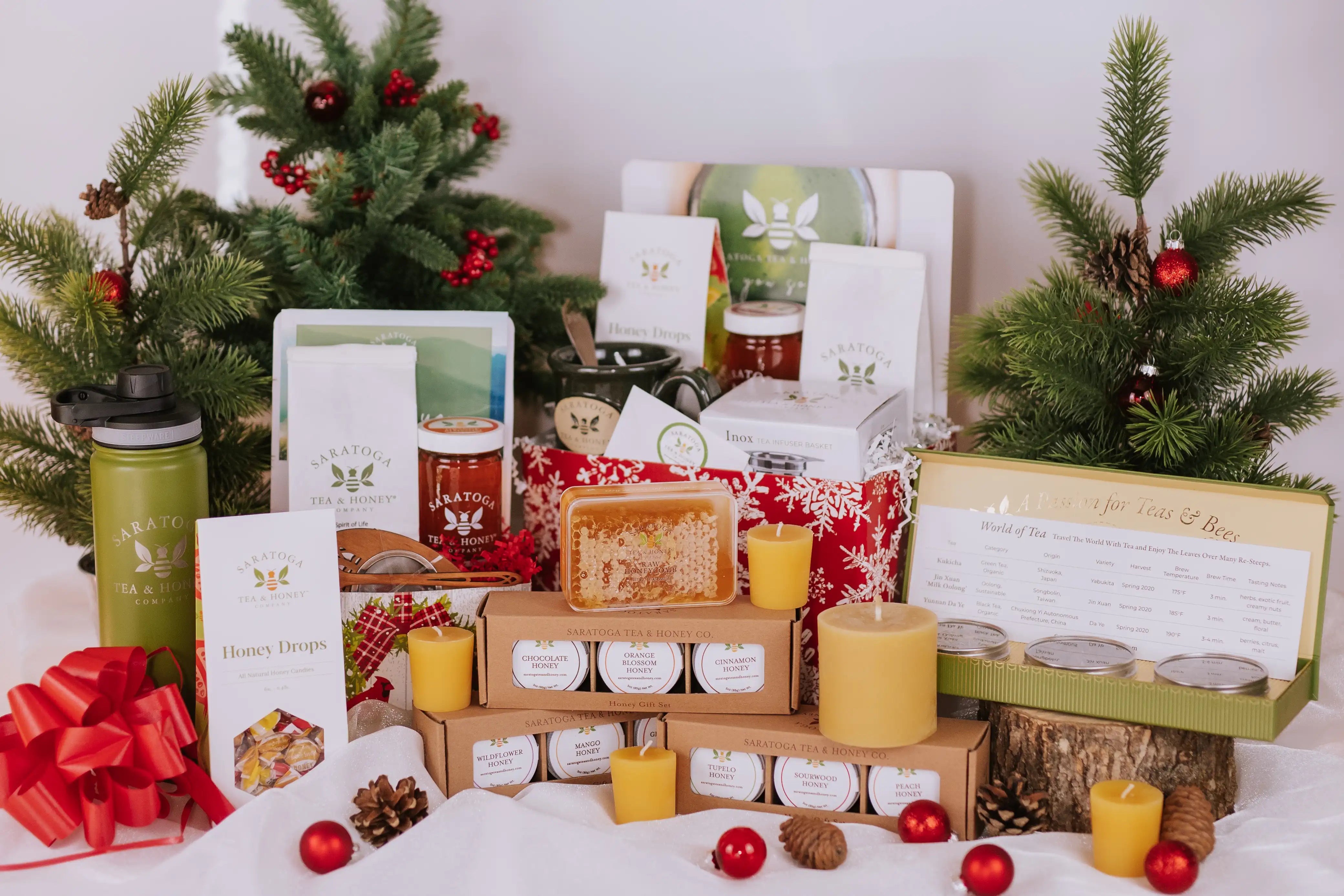 an array of gifts available from Saratoga Tea & Honey Co. including beeswax candles, honey candy, large and small gift baskets, honey comb, honey and tea trios, and a travel tea tumbler