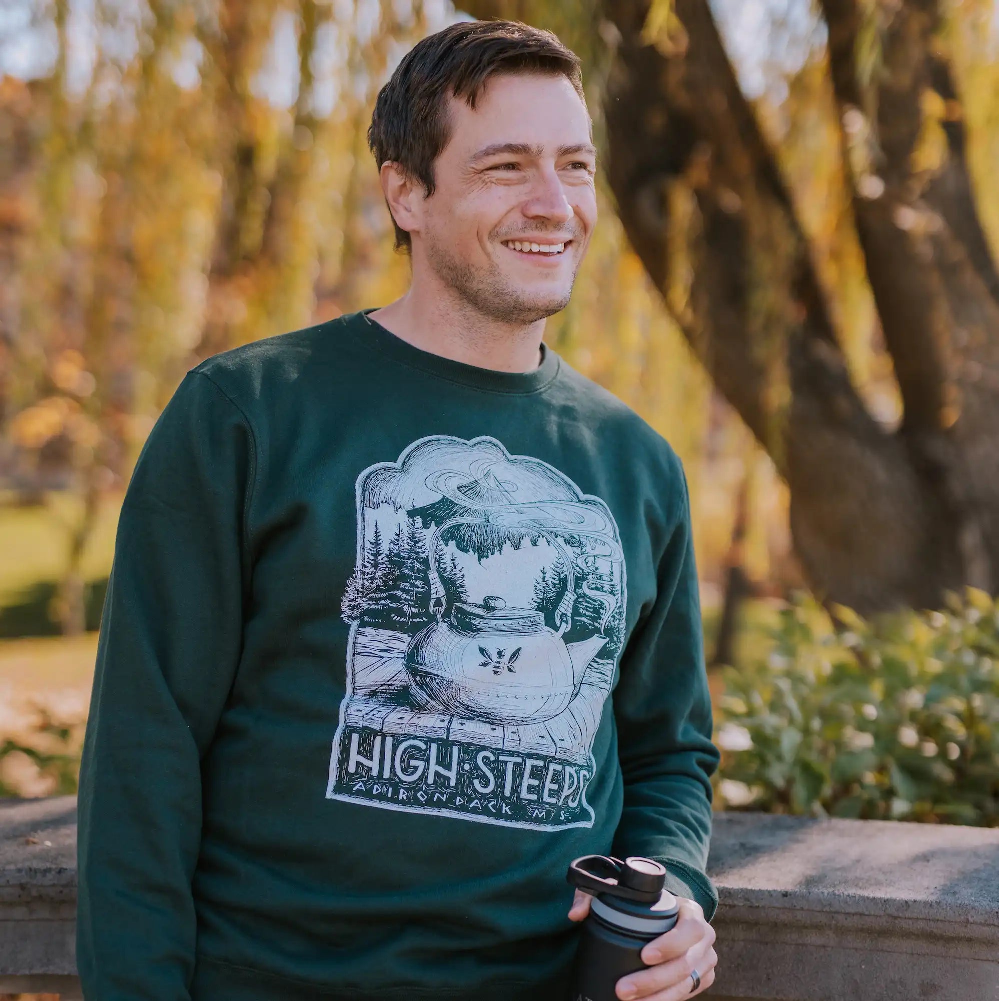 man wearing high steeps green tea pun sweatshirt with black saratoga tea and honey co tea tumbler