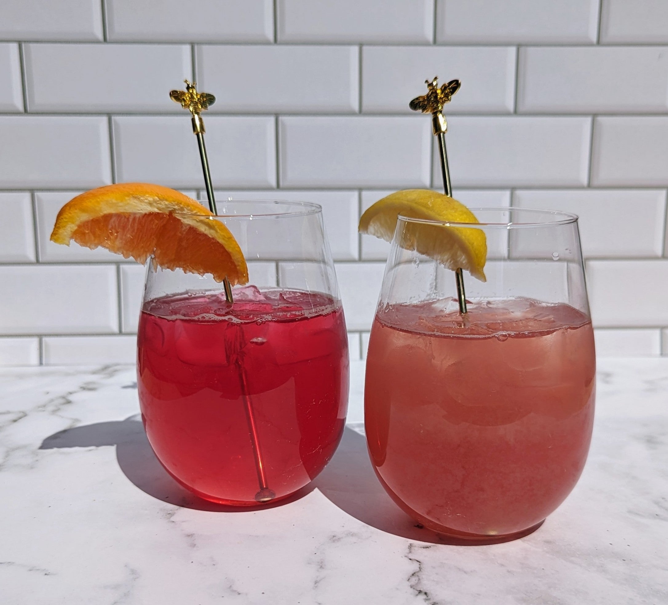 two tea spritzes with garnish and bee stir sticks