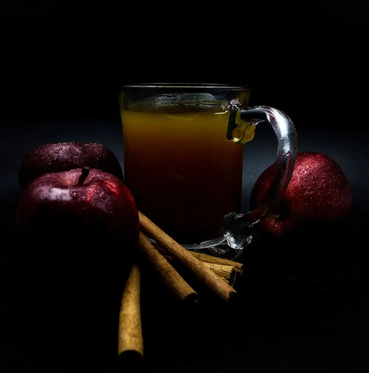mug of apple cider chai surrounded by apples and cinnamon sticks