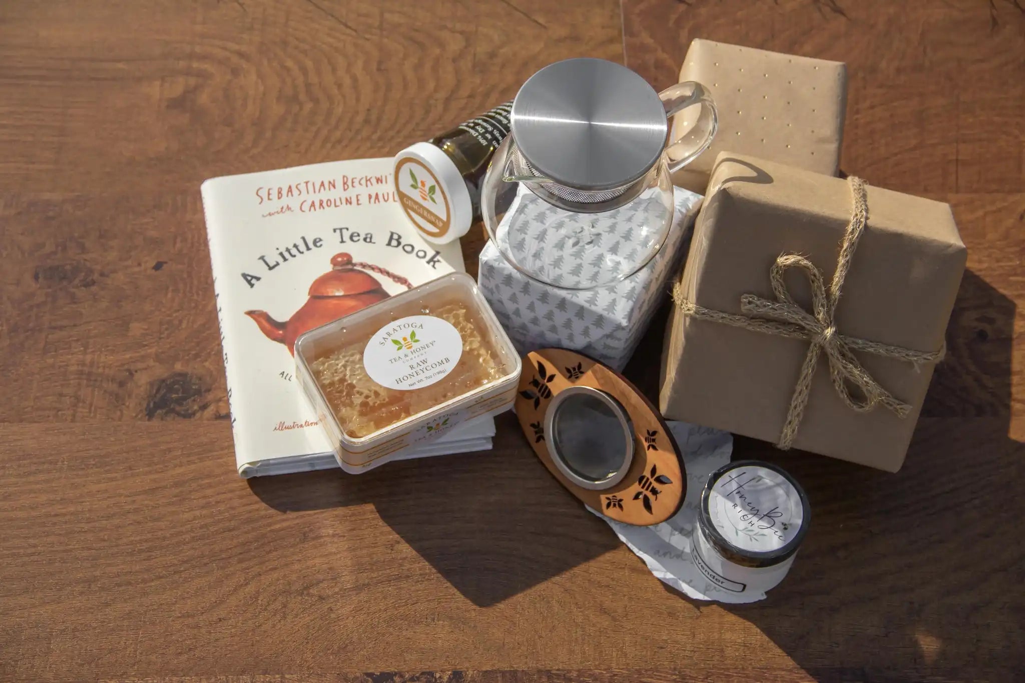 a collection of tea and honey gifts on a brown wood background with wrapped packages