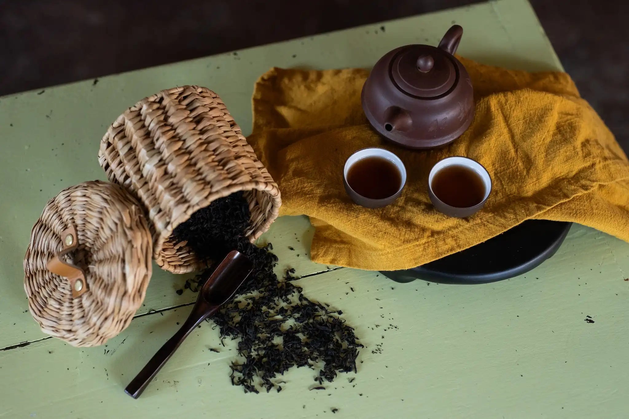 2020 Jeju aged shou puer stype tea spilled from basket next to yixing pot of tea and two small cups
