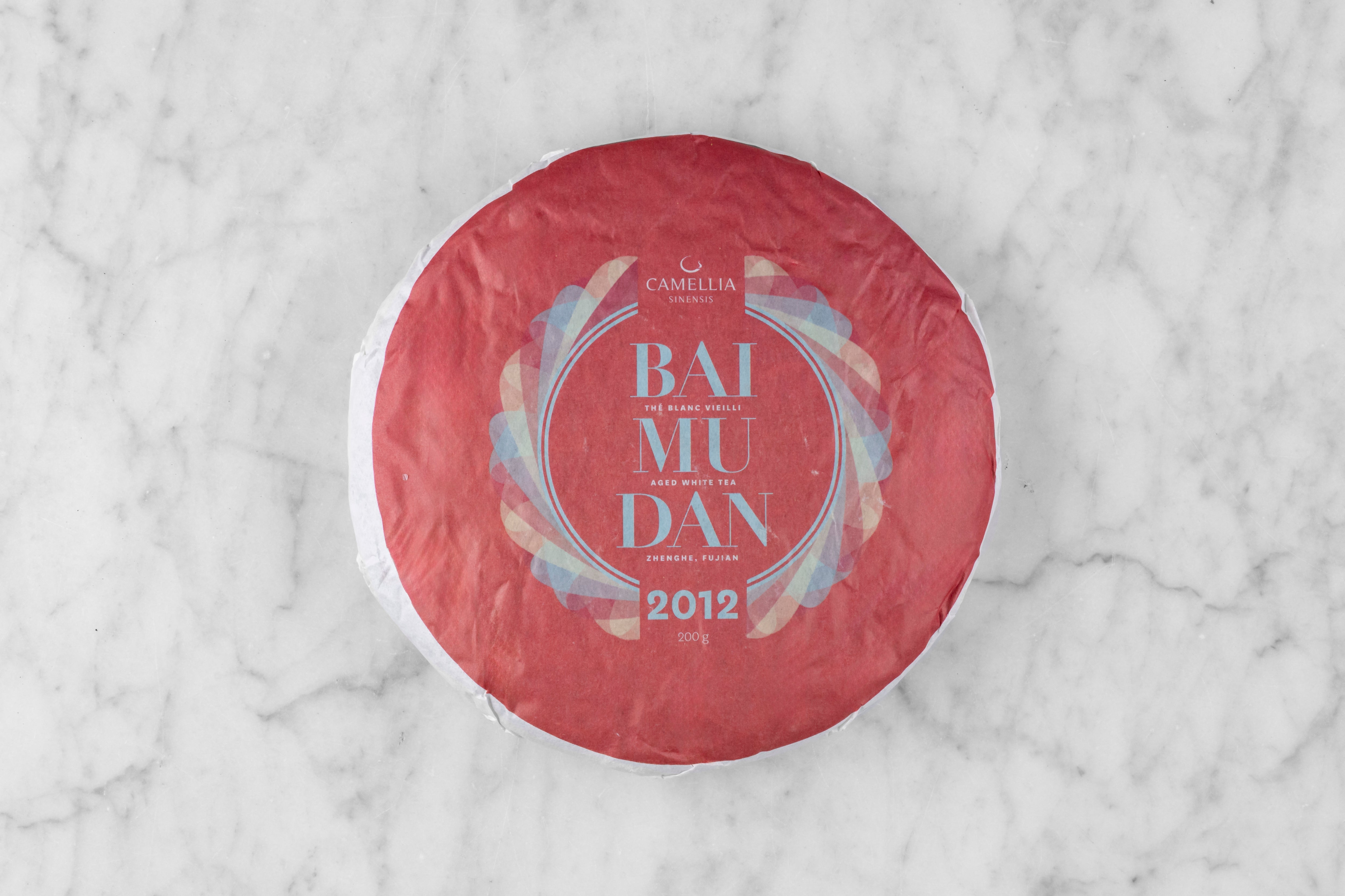 2012 Bai Mu Dan large, round tea cake wrapped in paper with the words "Bai Mu Dan 2012".
