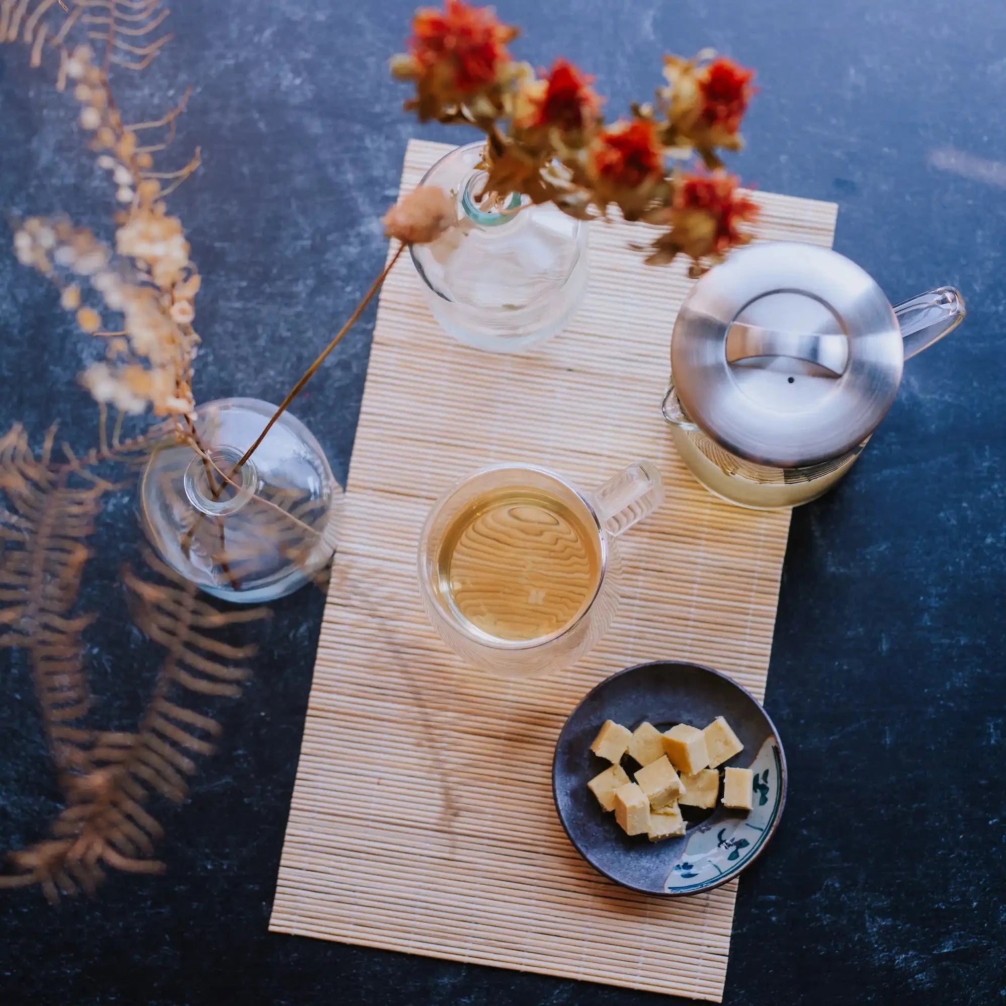 top down view of brewed green tea in a glass mug with mung bean cake squares and glass beaker