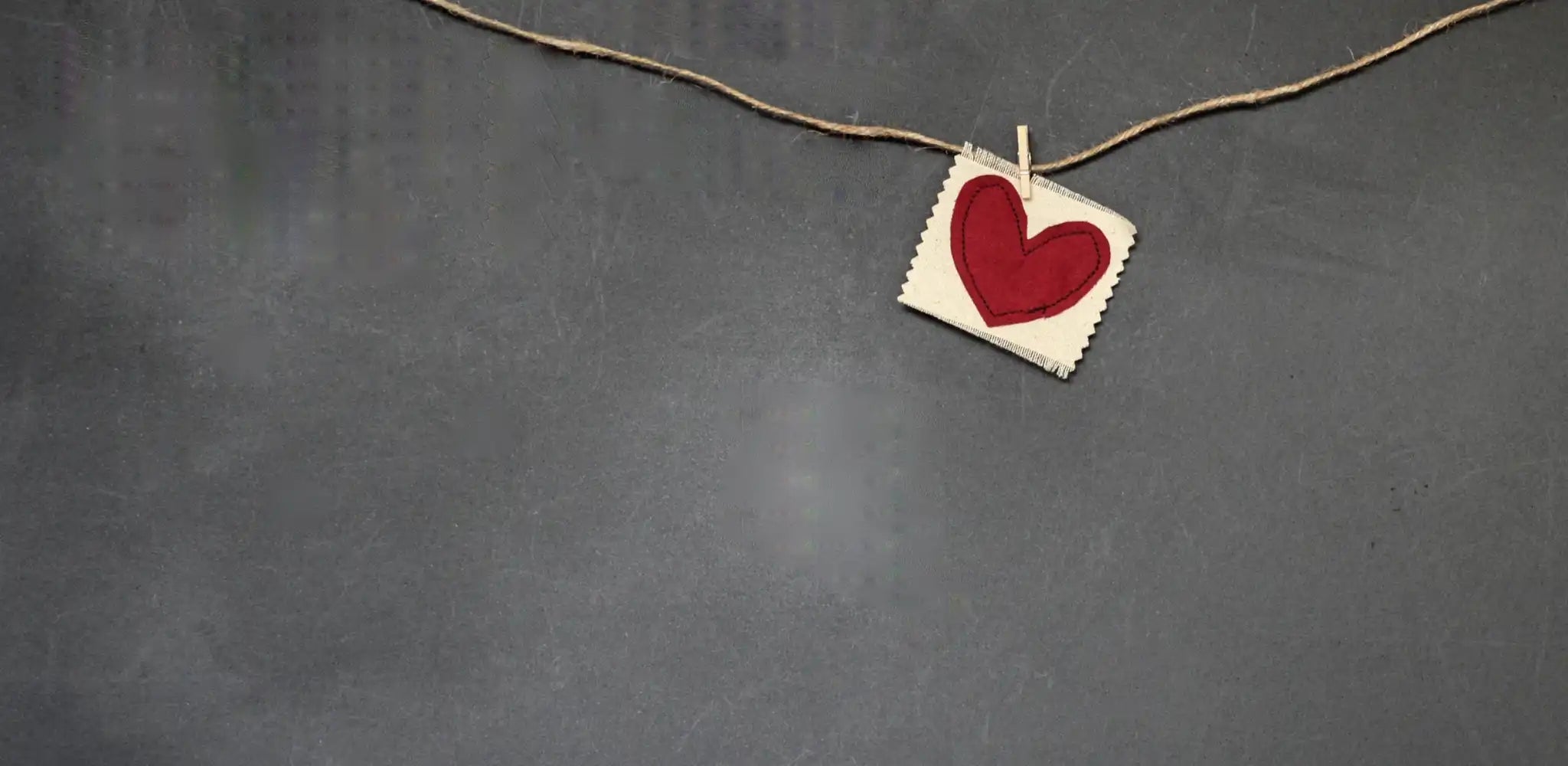 felt red heart clothespinned to twine on a slate background