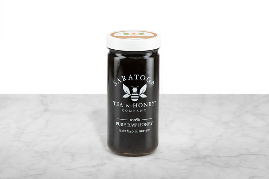 Opaque, black-brown Gingersnap Honey displayed in a 12oz cylindrical glass jar with a white lid. The logo and the words: "100% Pure Raw Honey" are printed on the jar.
