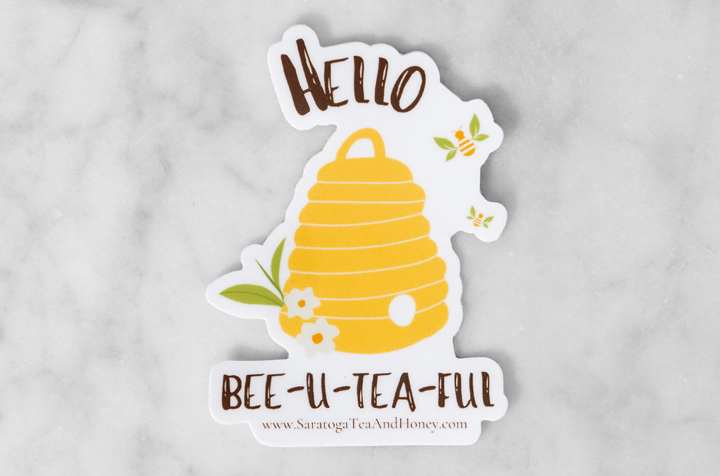 tea pun and honey pun vinyl sticker with illustration of a skep with bees, tea leaves, and flowers reading: hello bee-u-tea-ful