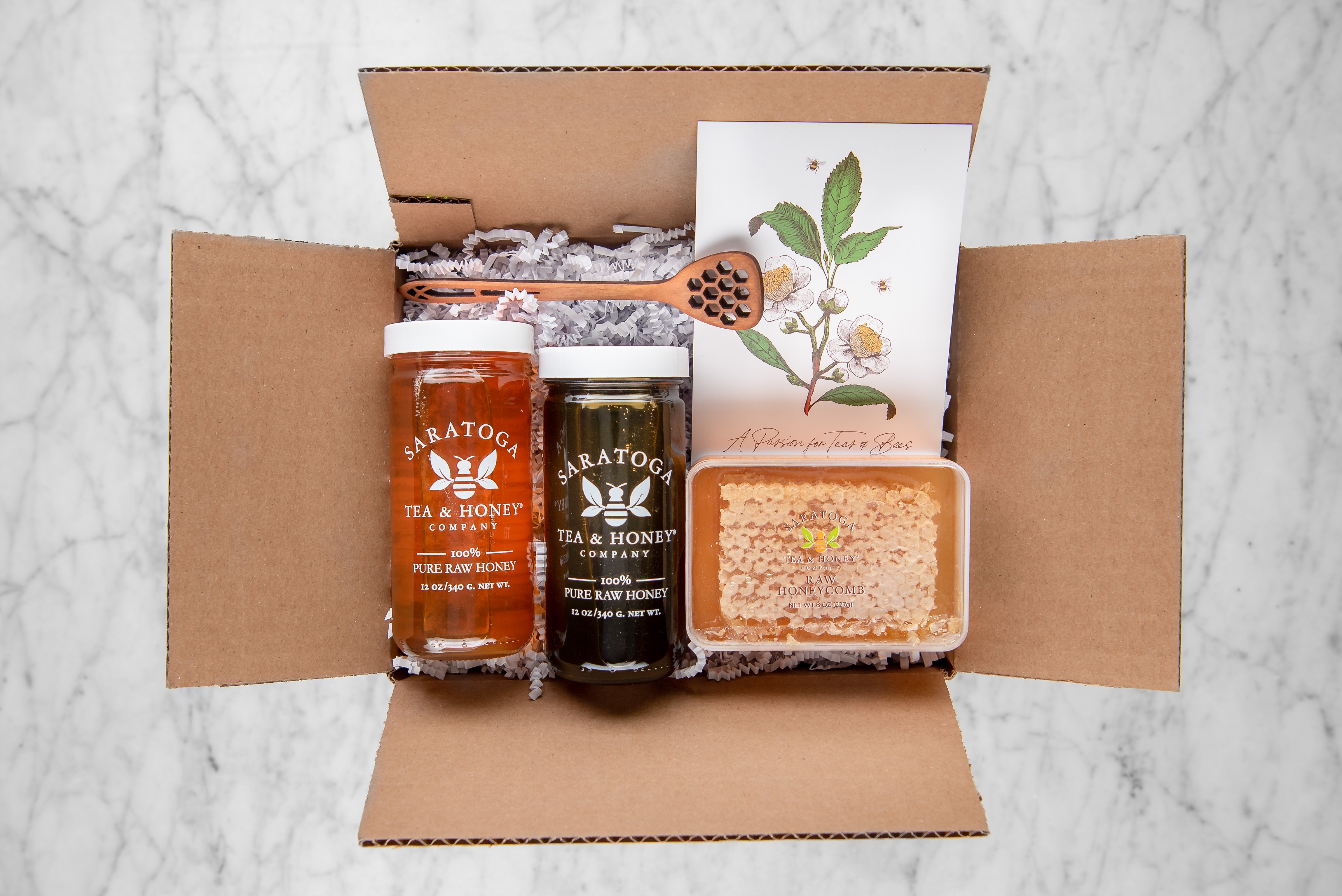 charcuterie honey gift set featuring one dark honey, one light honey, honey comb and a honey dipper made of cherrywood