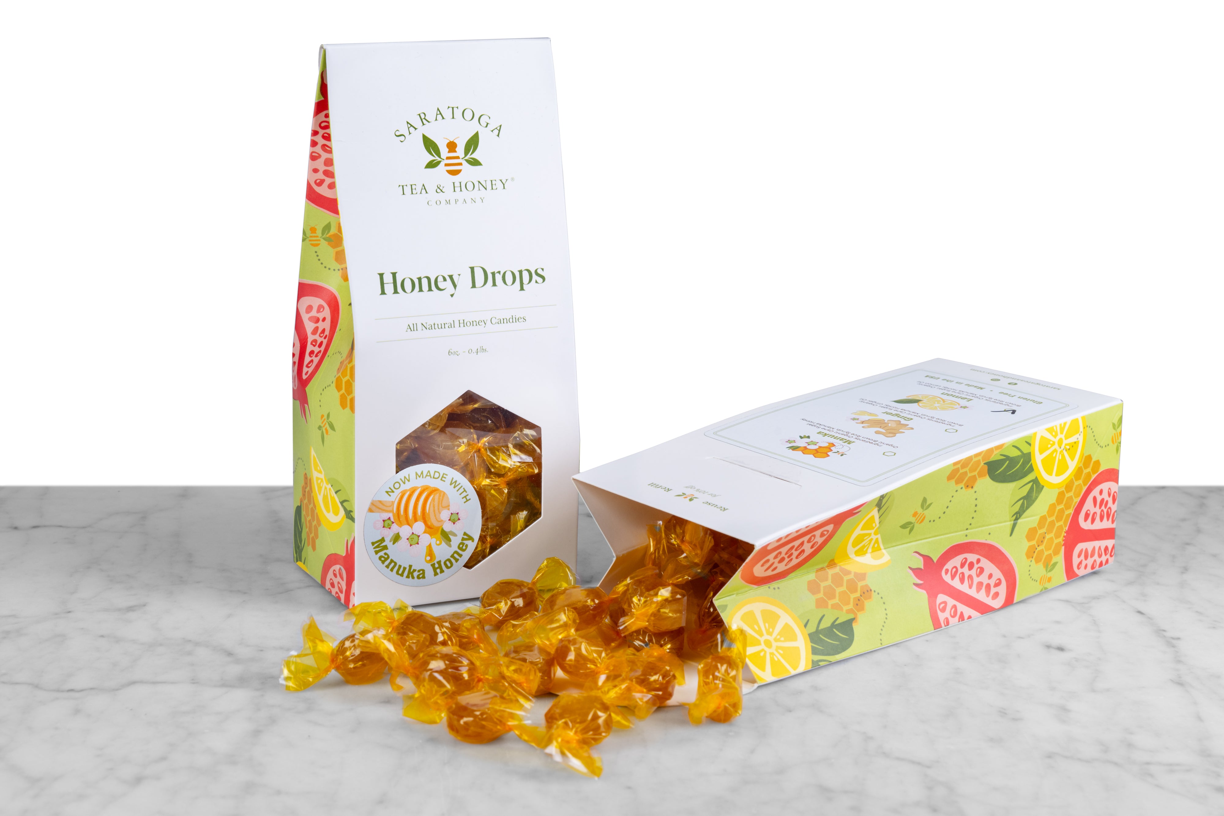 Front view of honey drop box with spilled box of lemon honey lozenges wrapped in yellow cellophane 
