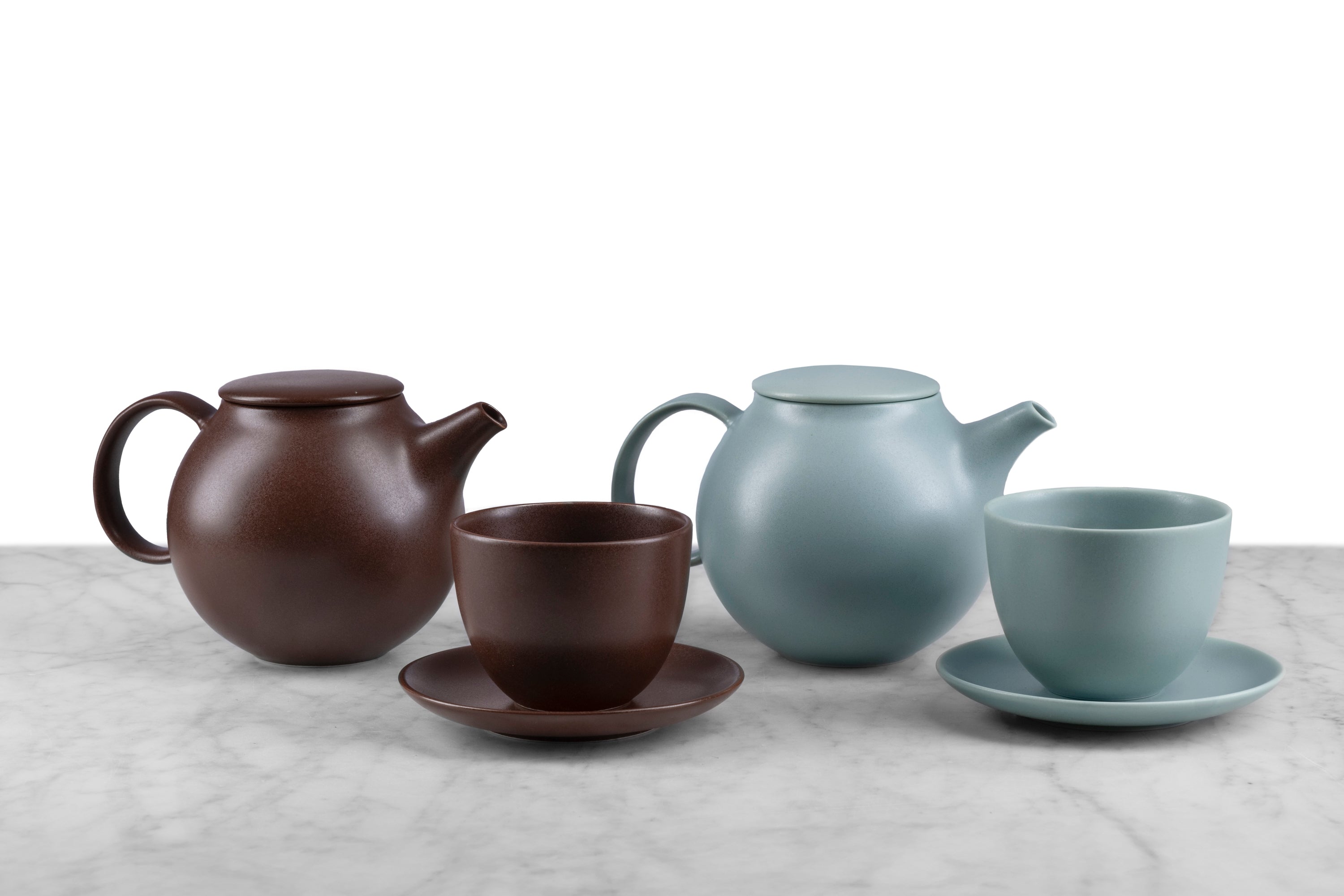 2 Kinto Pebble Tea Sets including teapot and cup and saucer. Left: Brown. Right: Moss Green.