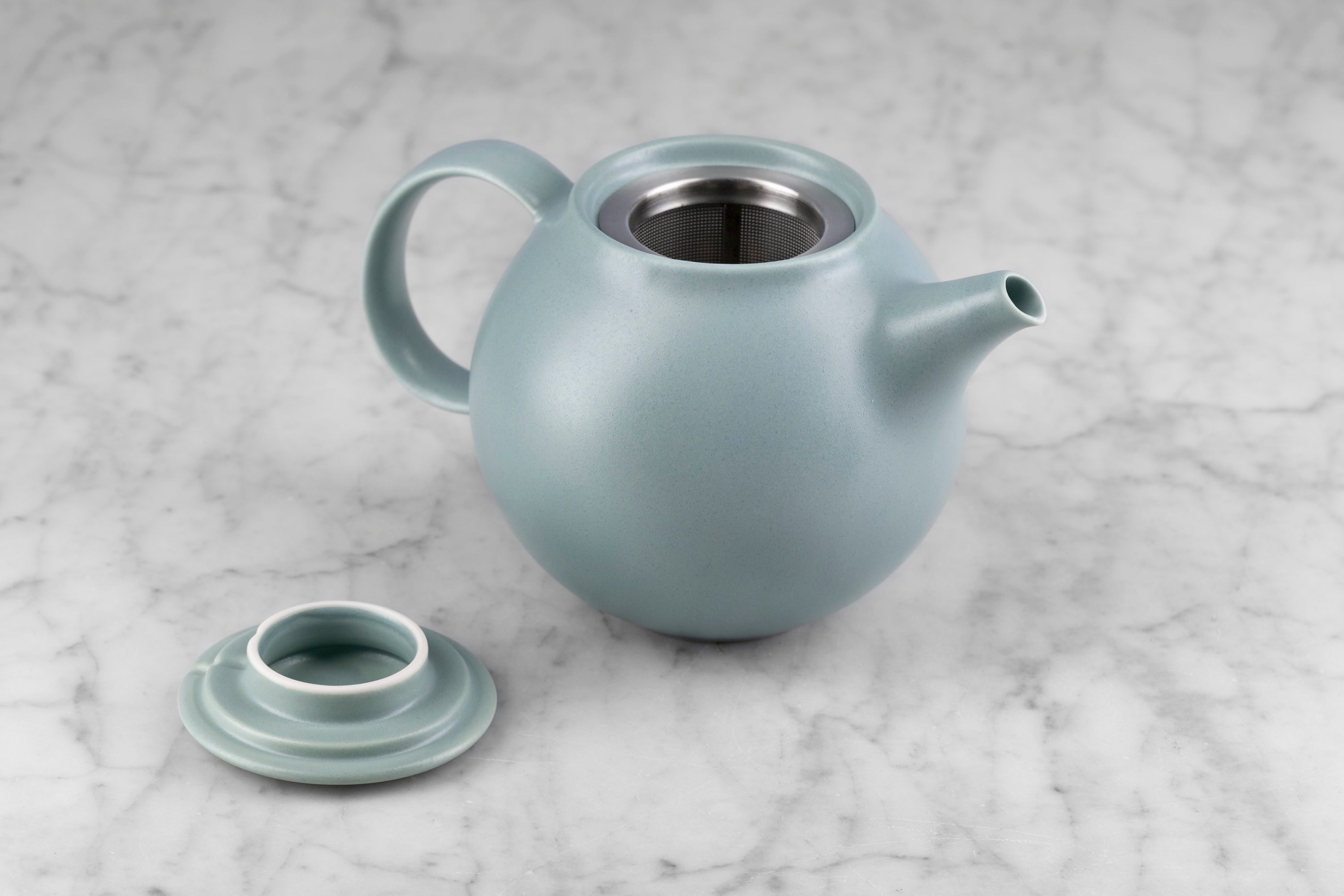 moss green kinto pebble modern Japanese teapot with lid off to show included infuser sitting on a marble background
