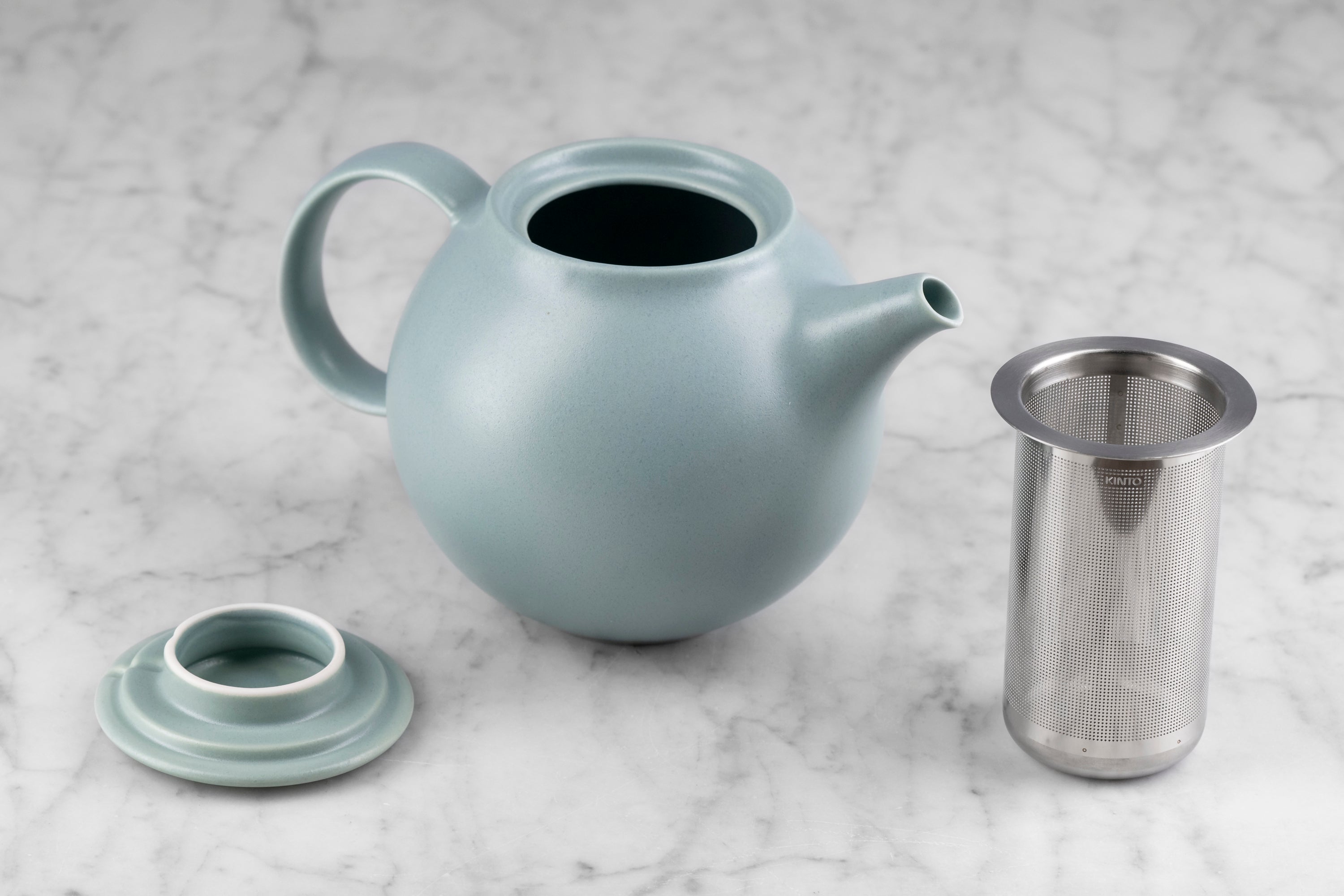 moss green kinto pebble modern Japanese teapot on marble background with lid and infuser