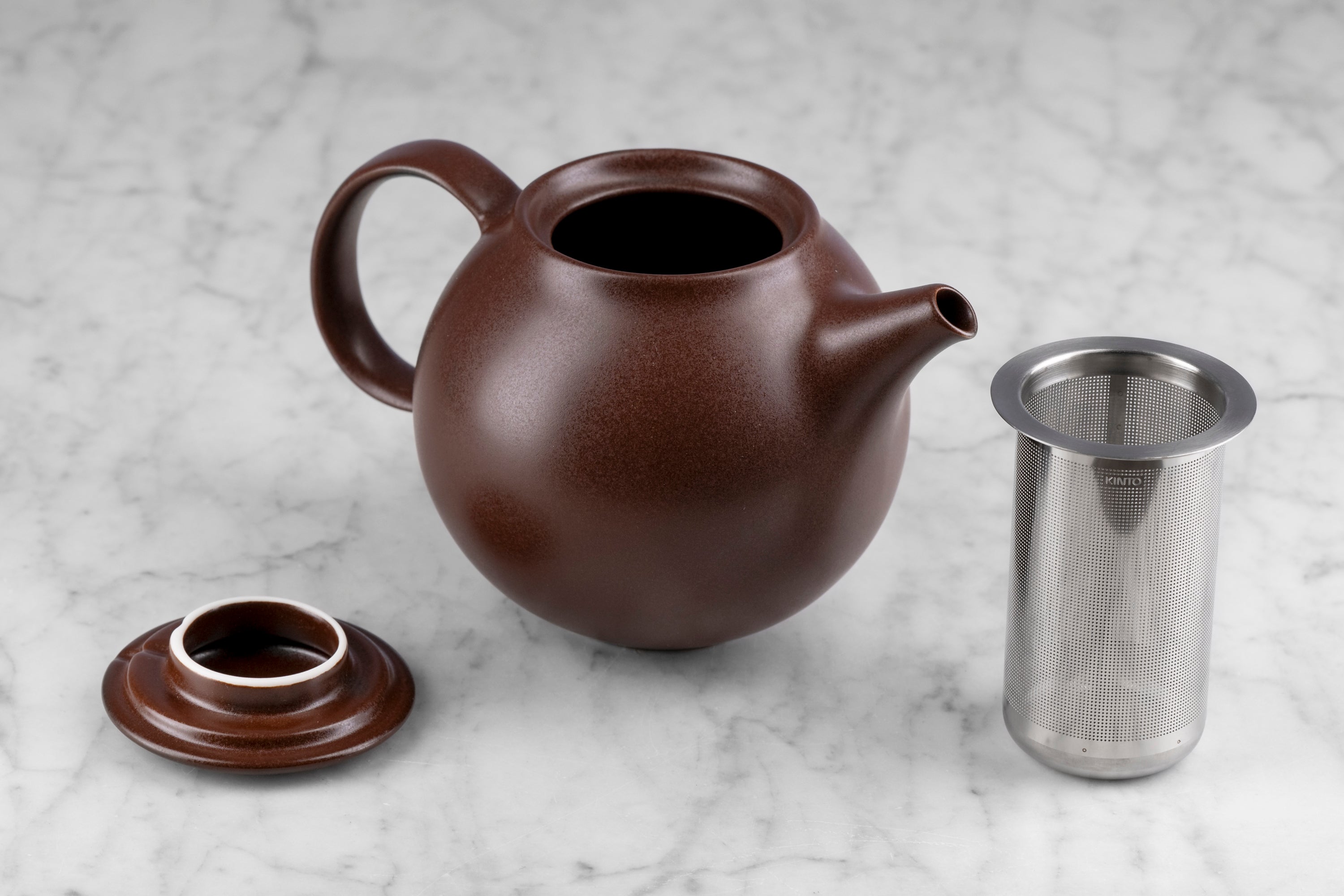 brown kinto pebble modern Japanese teapot on marble background with lid and infuser