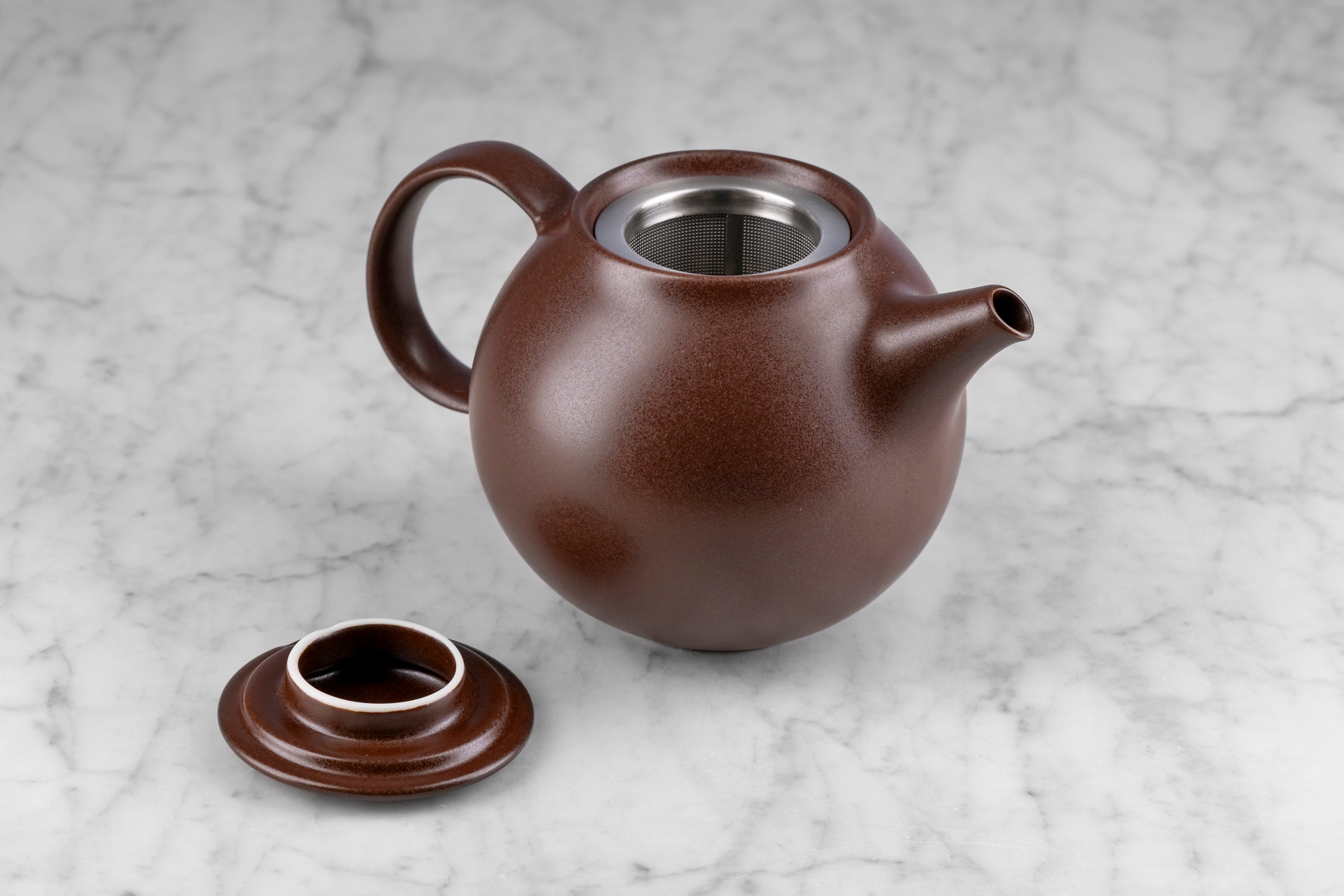 brown kinto pebble modern Japanese teapot with lid off to show included infuser sitting on a marble background