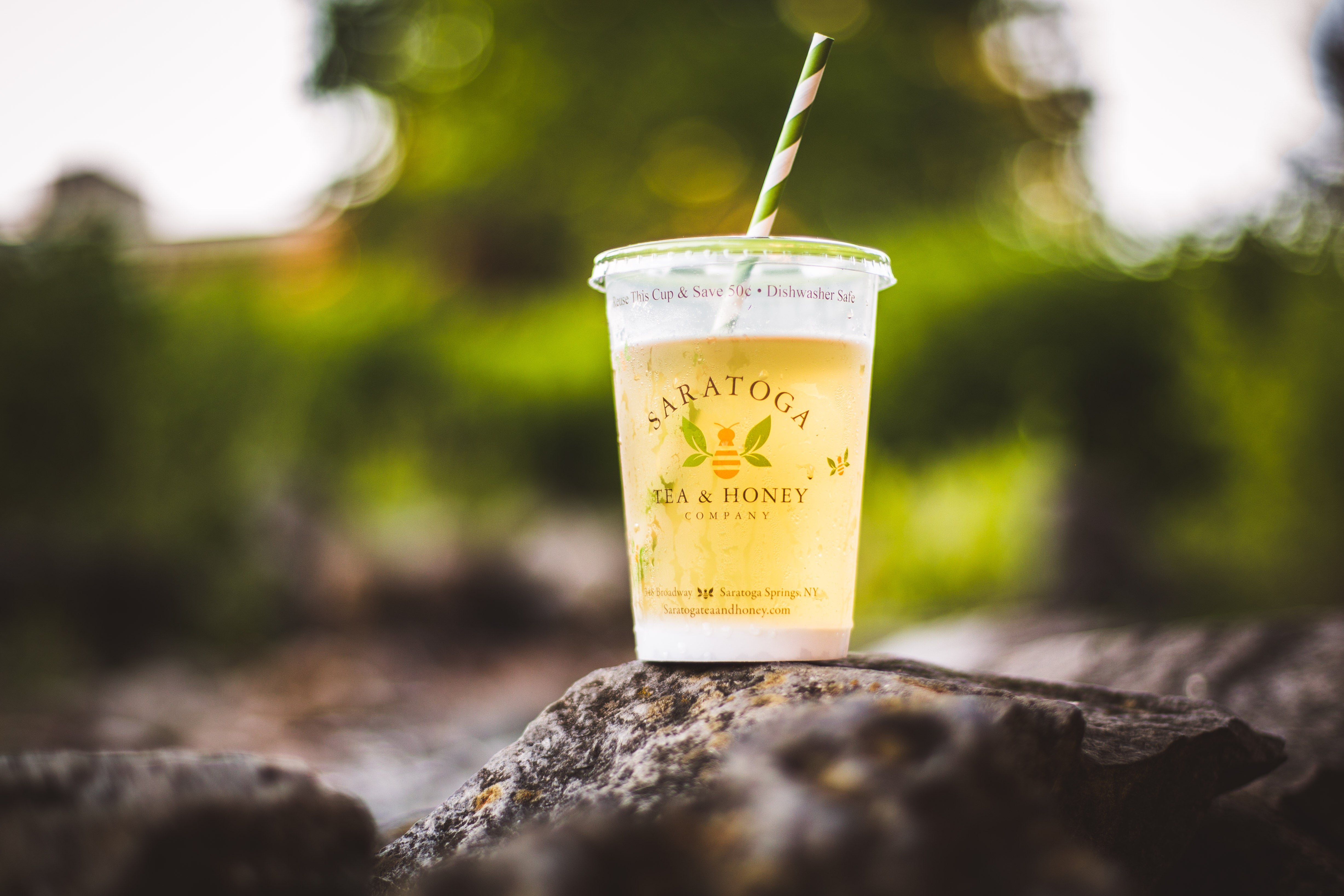 iconic reusable saratoga tea & honey co iced tea cup filled with green tea on a rock