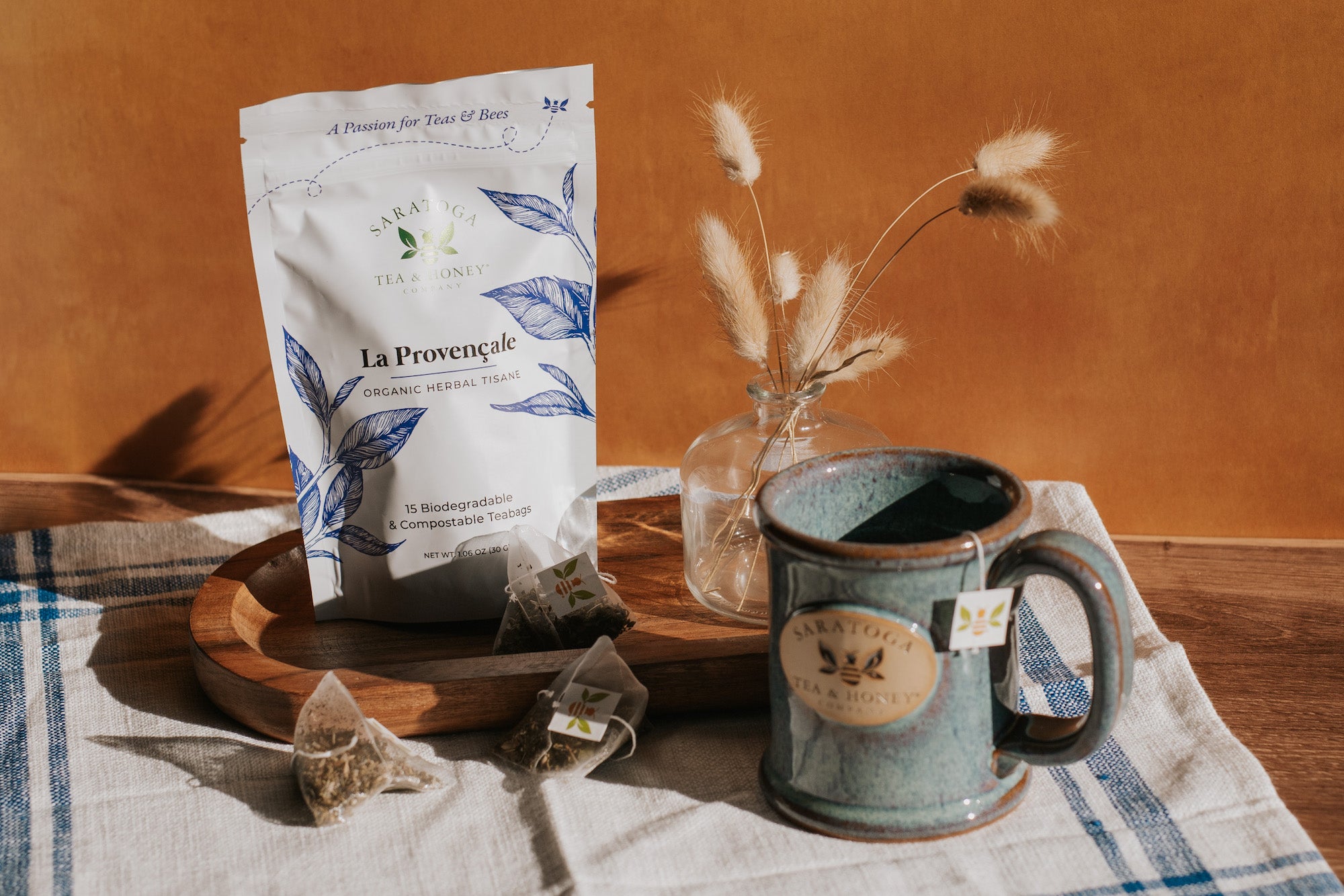 Aesthetic scene of La Provençale tea bags, a pouch of tea, and a stoneware Saratoga Tea & Honey Co. mug.