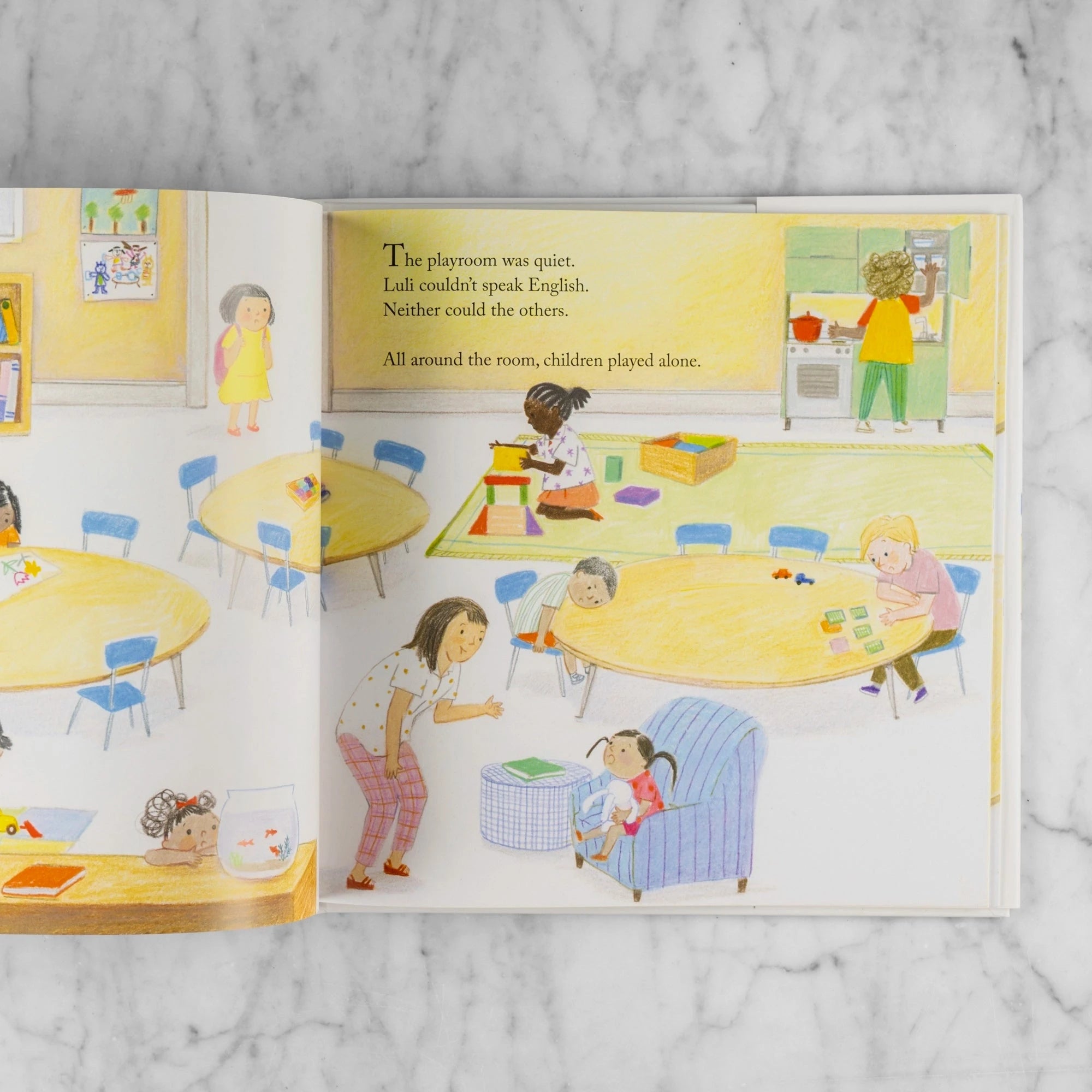 Story excerpt from Luli and the Language of Tea. Shows children playing alone in a classroom. Reads: "The playroom was quiet. Luli couldn't speak English. Neither could the others. All around the room, children played alone."