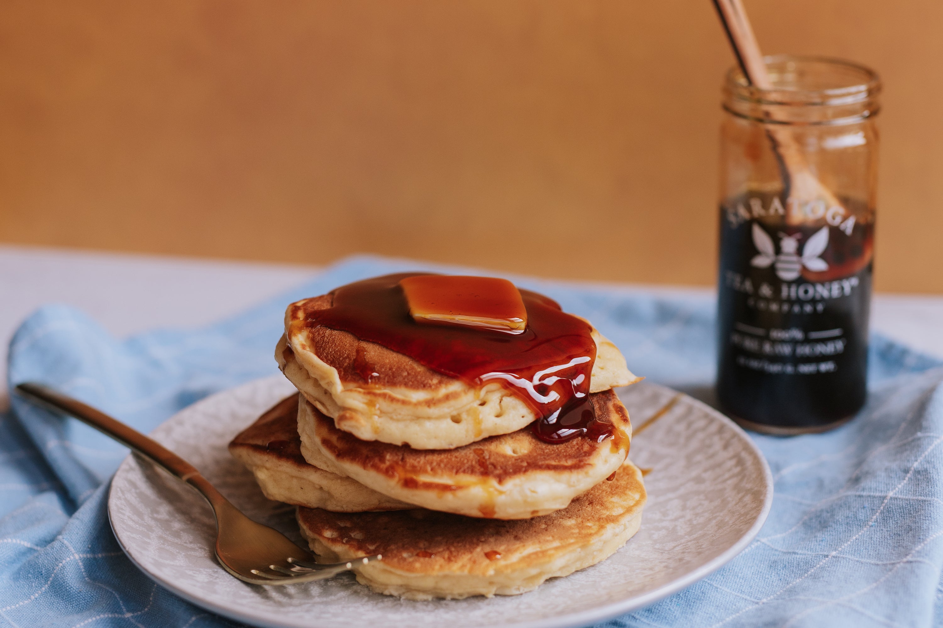 fluffy pancakes with a pat of butter and smothered in cinnamon infused honey