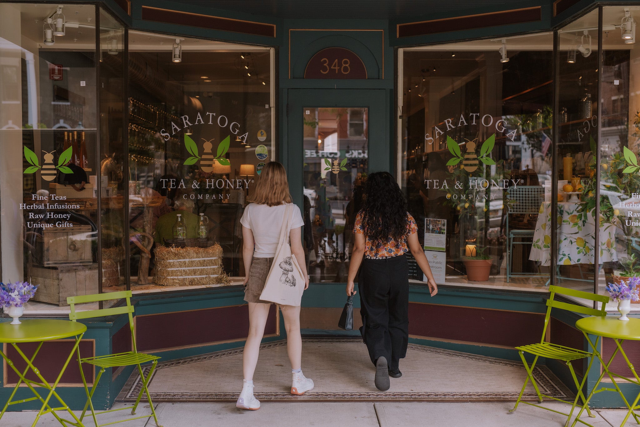 two young women walking into the doors of Saratoga Tea & Honey Co.