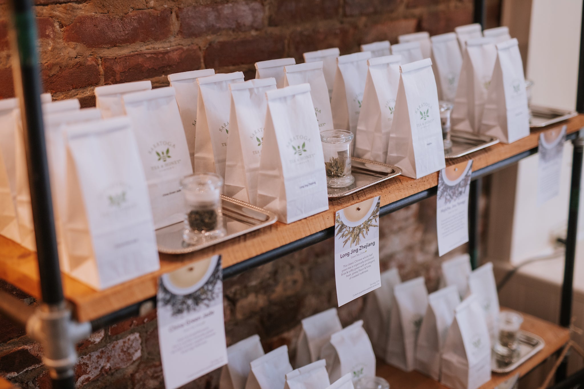 view of white Saratoga Tea & Honey Co. bags of loose leaf tea on a shelf at the flagship store