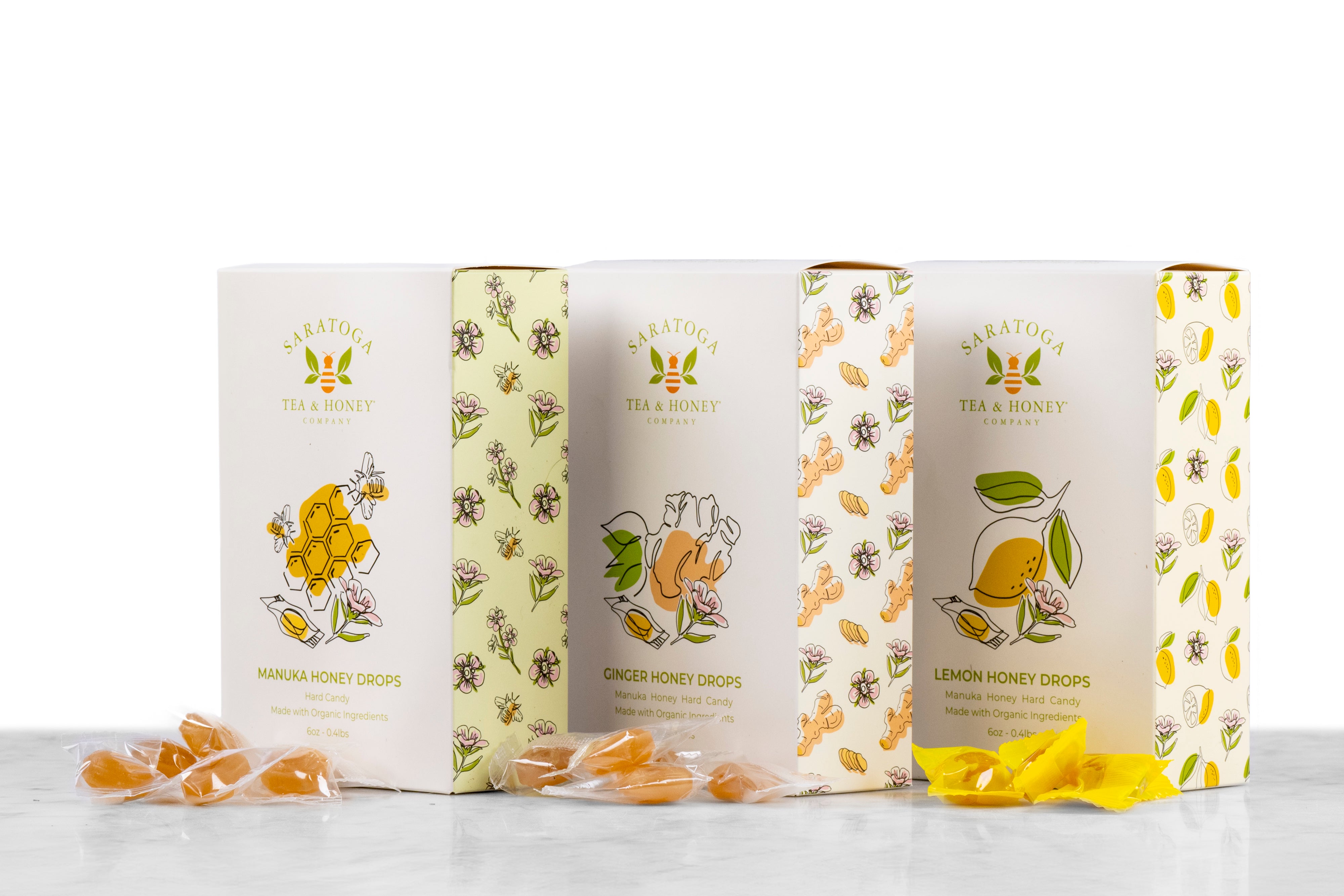 three boxes of honey candy with piles of wrapped candies from Saratoga Tea & Honey Co. from left to right: manuka, ginger, lemon