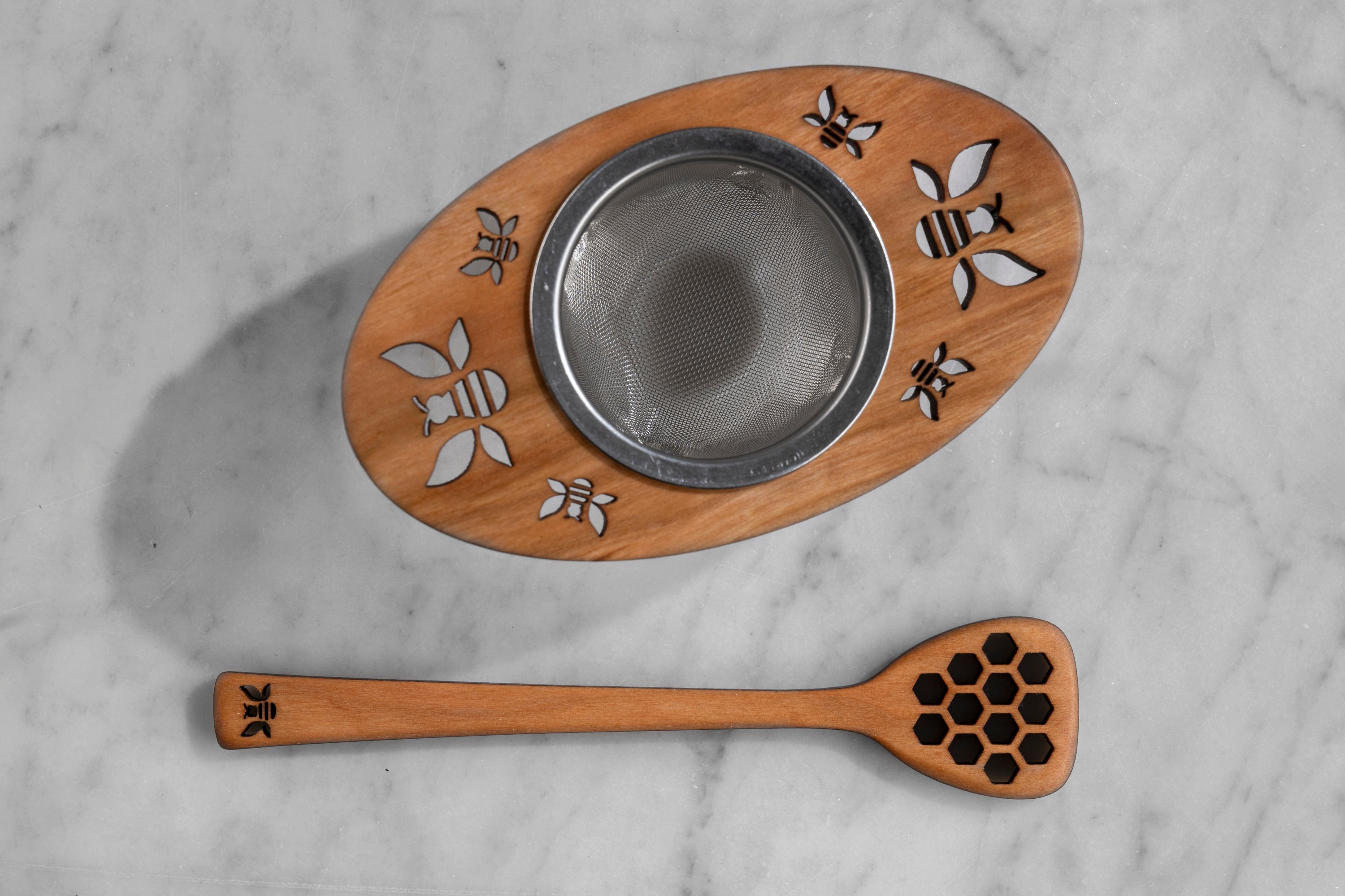 top down view of wooden and metal tea infuser and wooden honey dipper with bee motif
