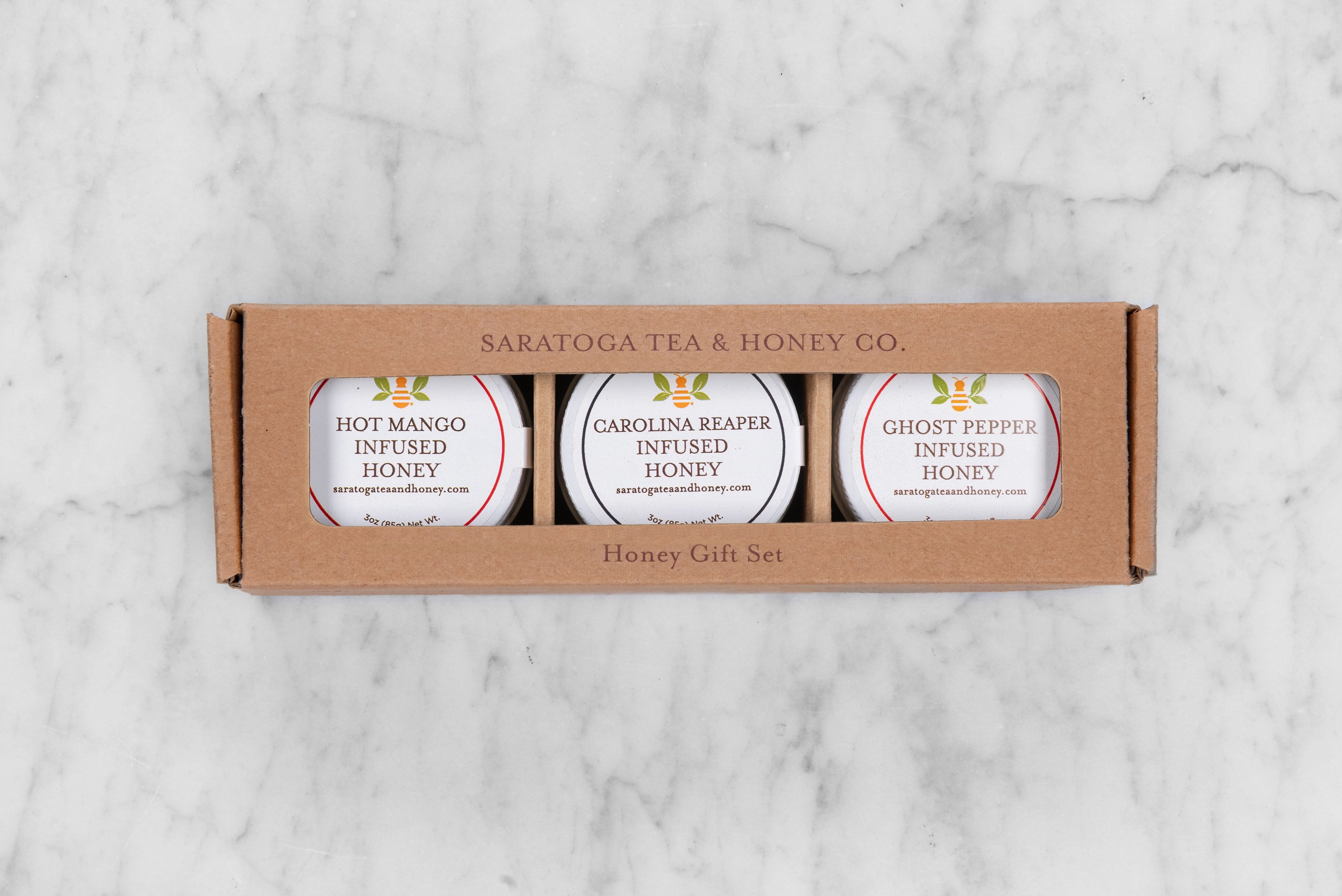 kraft box with an opening showing three mini honey jars of hot honey labeled: Hot Mango Infused Honey, Carolina Reaper Infused Honey, and Ghost Pepper Infused Honey.