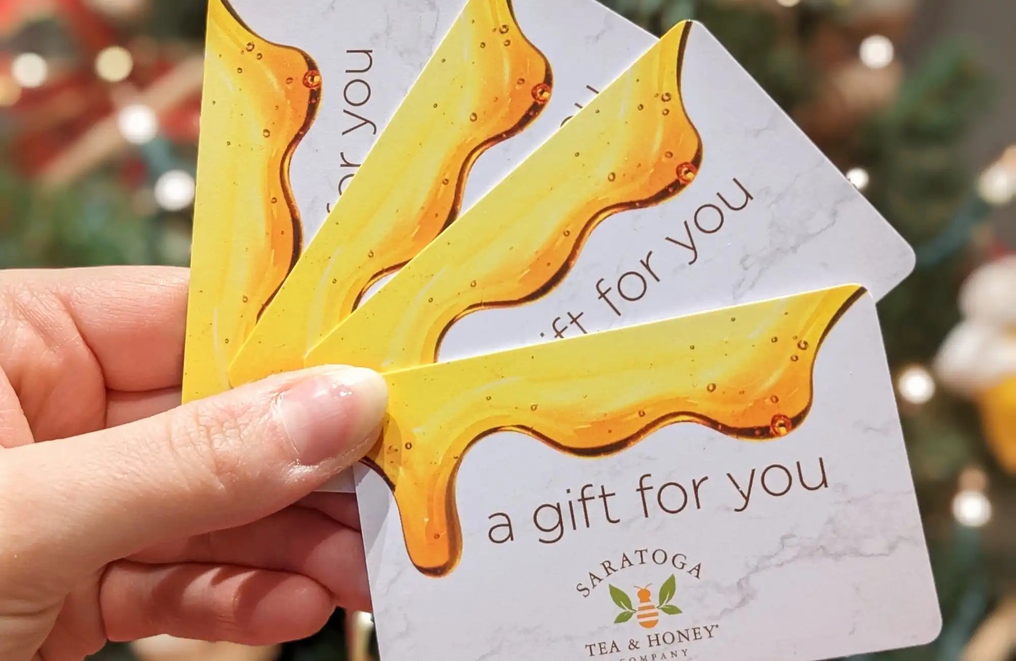 hand holding a spray of saratoga tea and honey co. gift cards