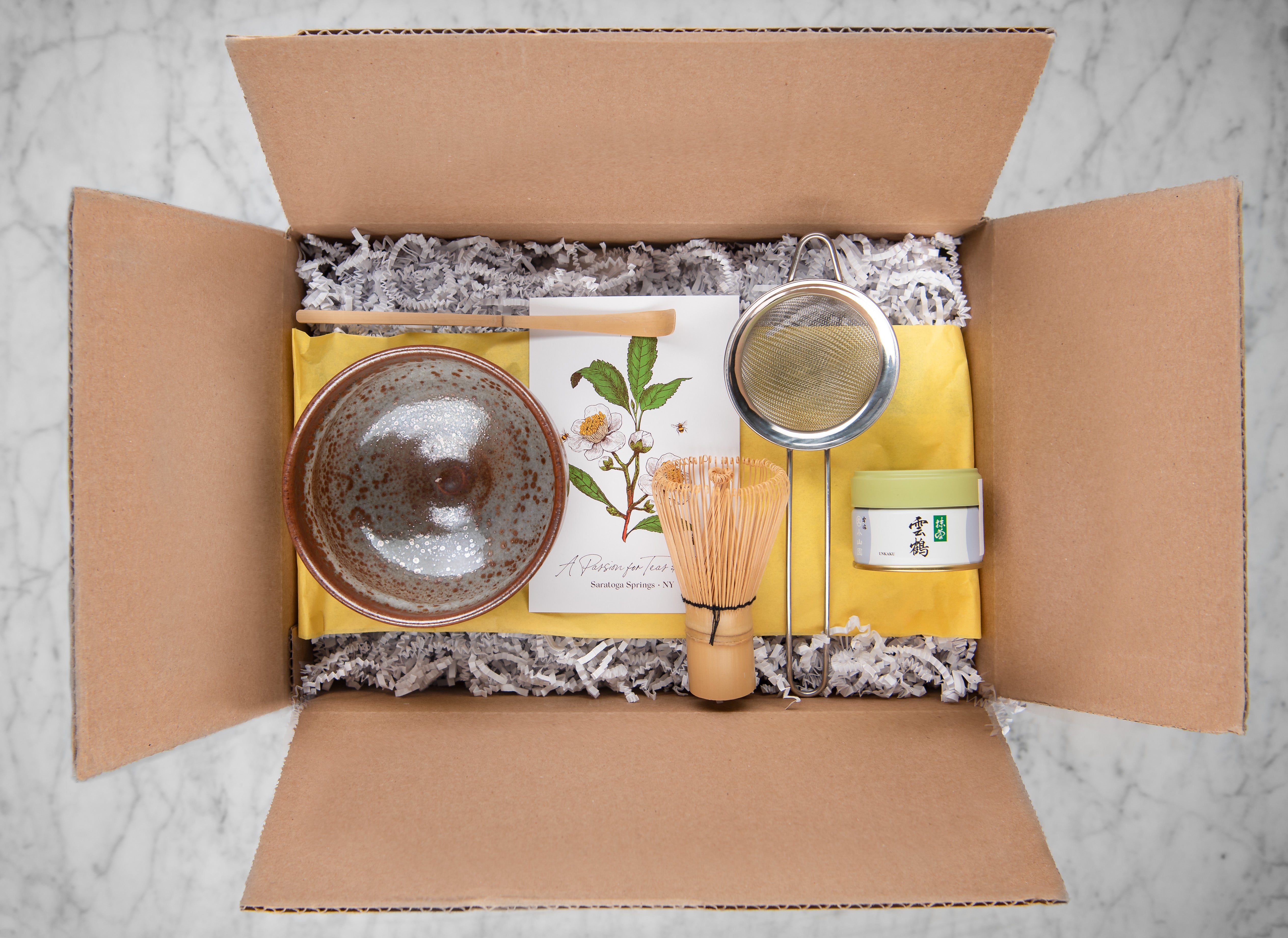 gift box with decorative fill featuring hand-thrown matcha bowl, bamboo matcha scoop, bamboo matcha whisk, stainless steel mesh strainer and usucha grade matcha wako from 8th generation matcha producer