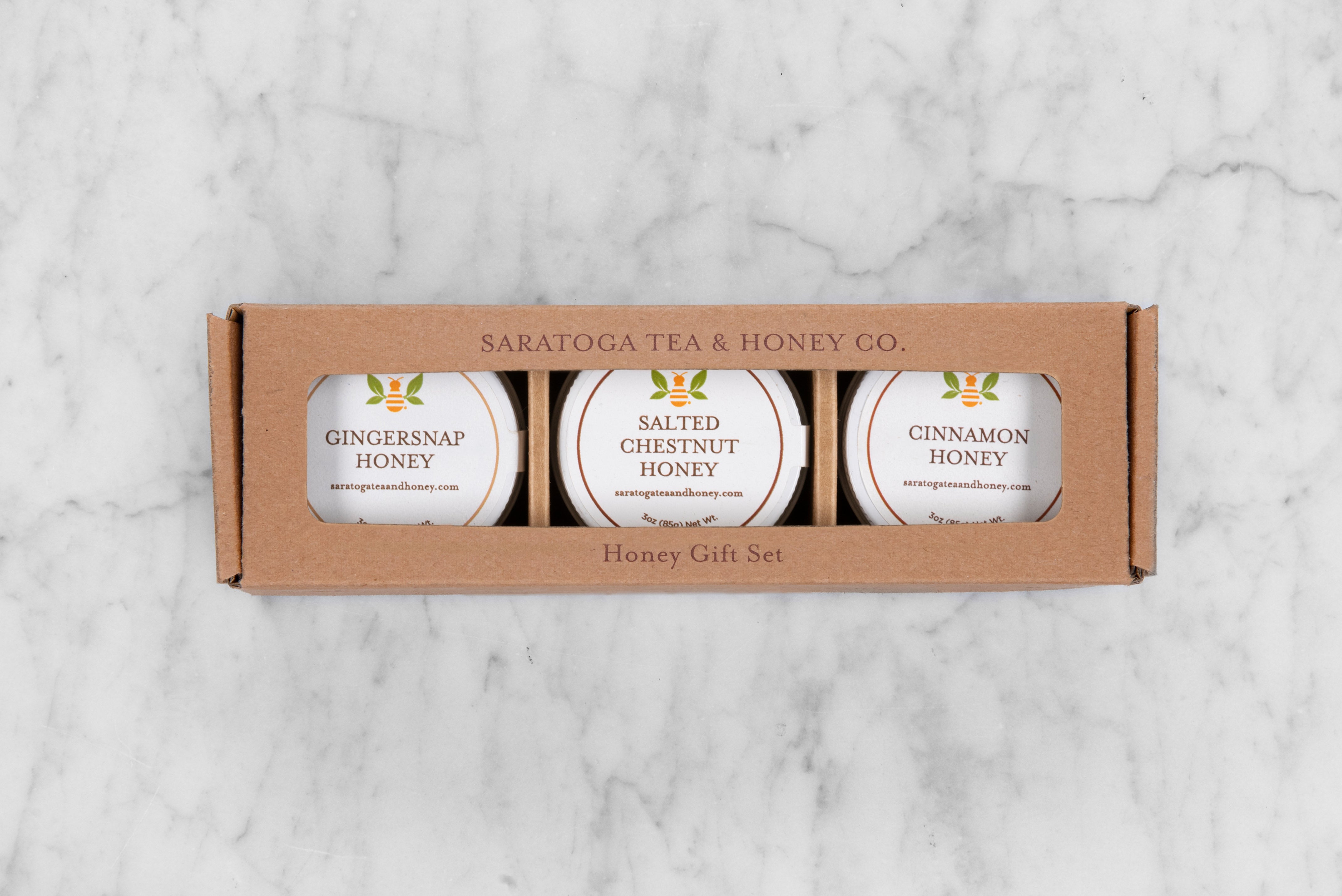 three pack honey gift set in a brown craft box reading Saratoga Tea & Honey Co. Honey Gift Set. From left to right: Gingersnap Honey, Salted Chestnut Honey, Cinnamon Honey