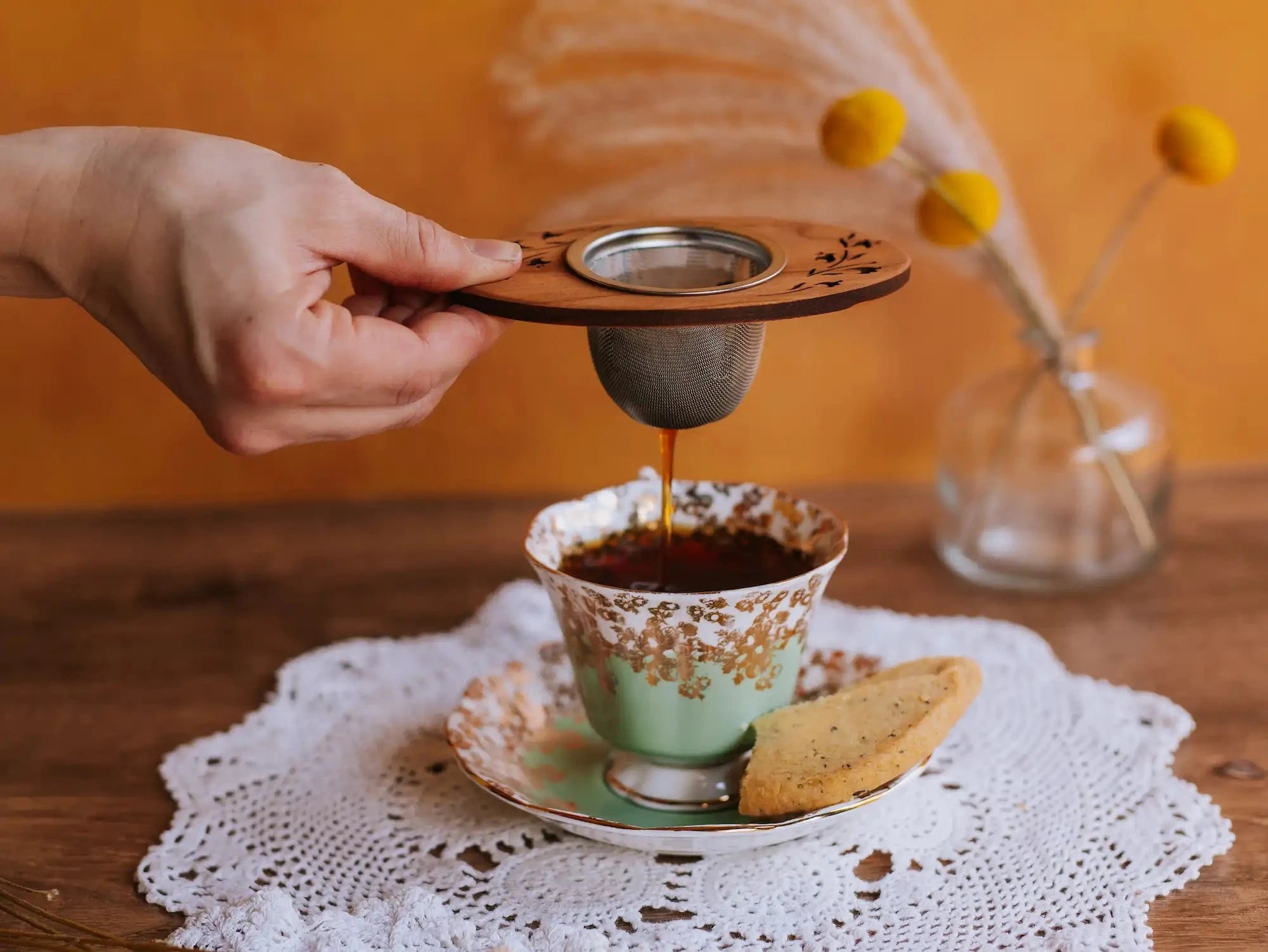 hand pulling an infuser out of a vintage cup of brewed tea