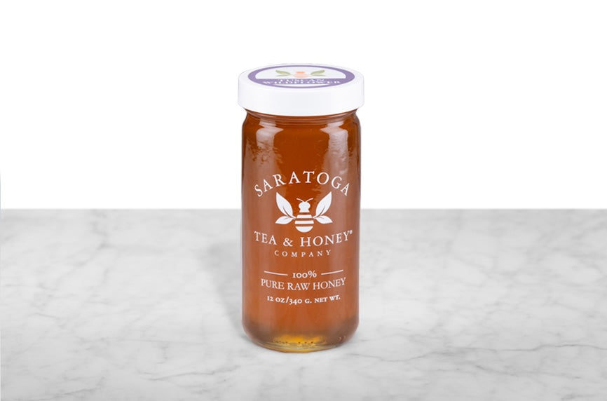 Amber Italian wildflower honey in a 12oz clear glass jar branded with the Saratoga Tea & Honey Co. logo and a white top. The logo and the words: "100% Pure Raw Honey" are printed on the jar.