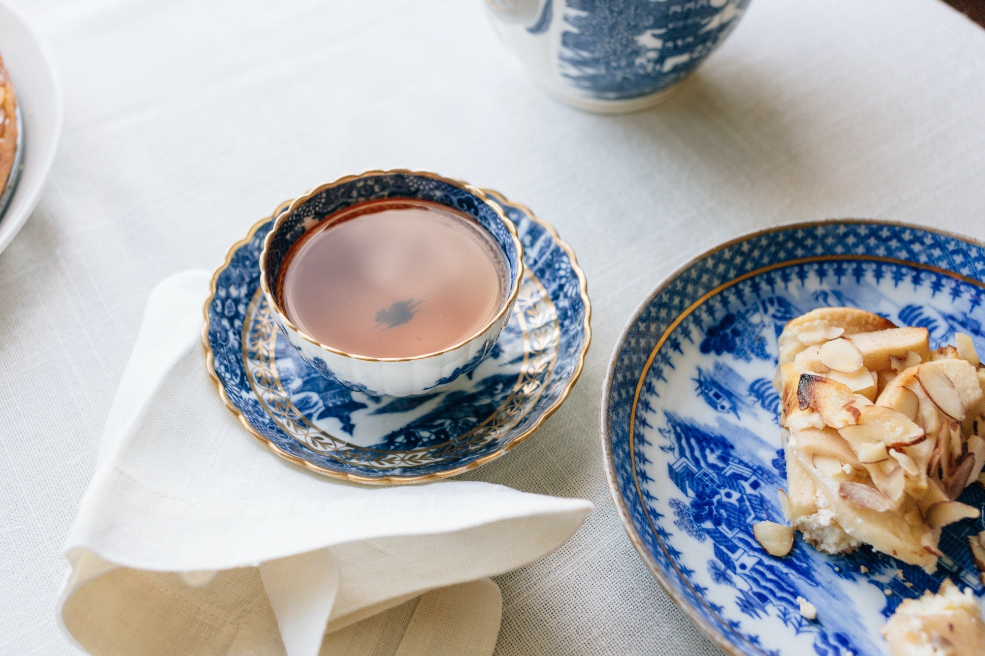 cup of tea in blue vintage teaware with a plate of almond croissant