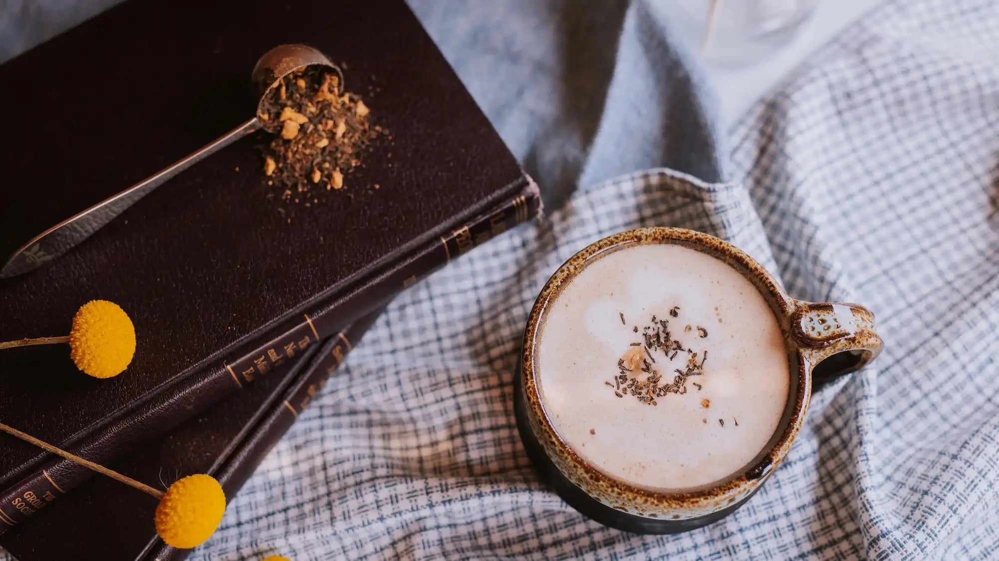 mug of chai latte with spilled loose leaf chai on a stack of books