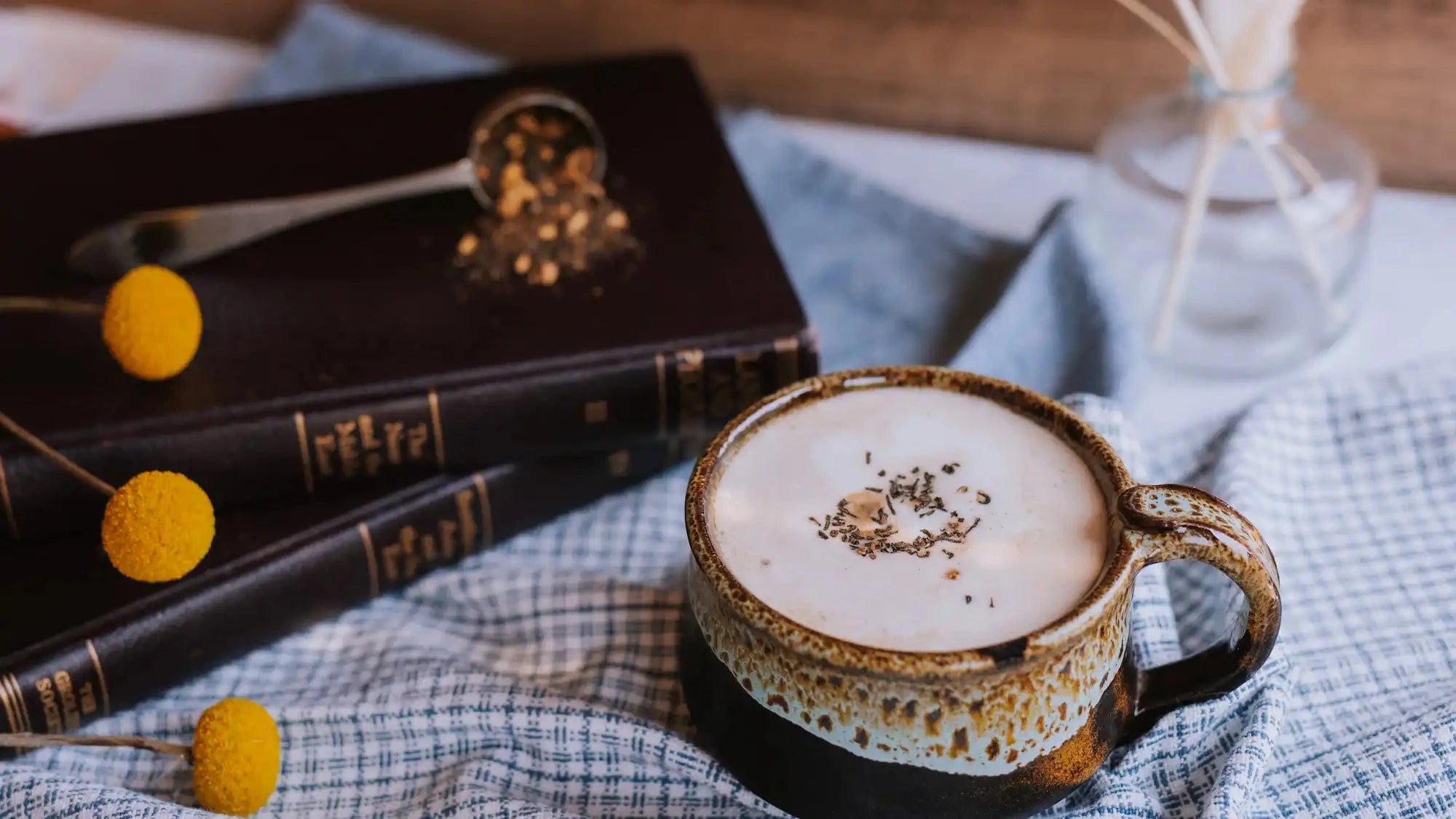 chai latte in stoneware mug with books and blue linens