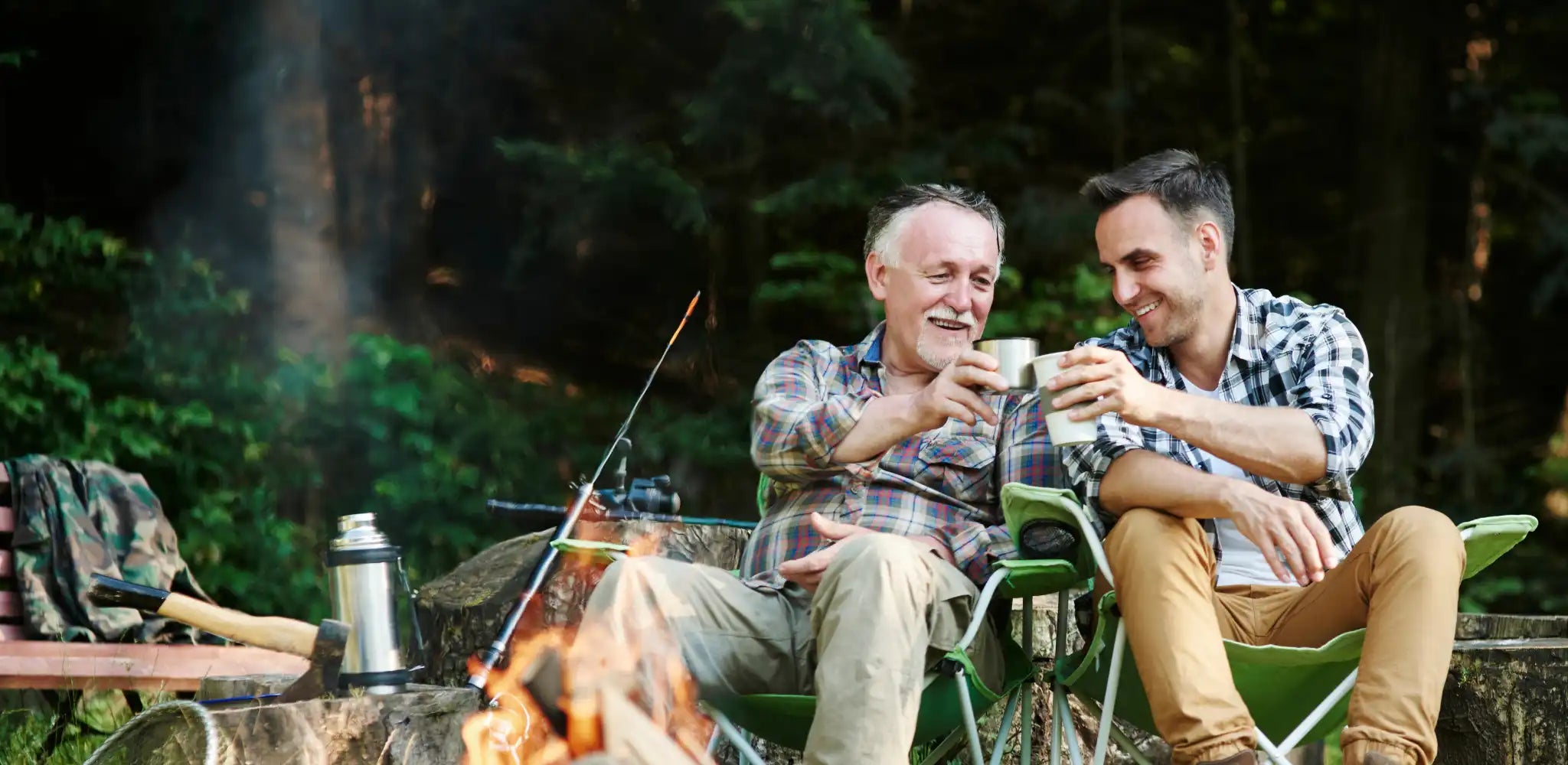 father and son toasting hot beverages in front of a campfire