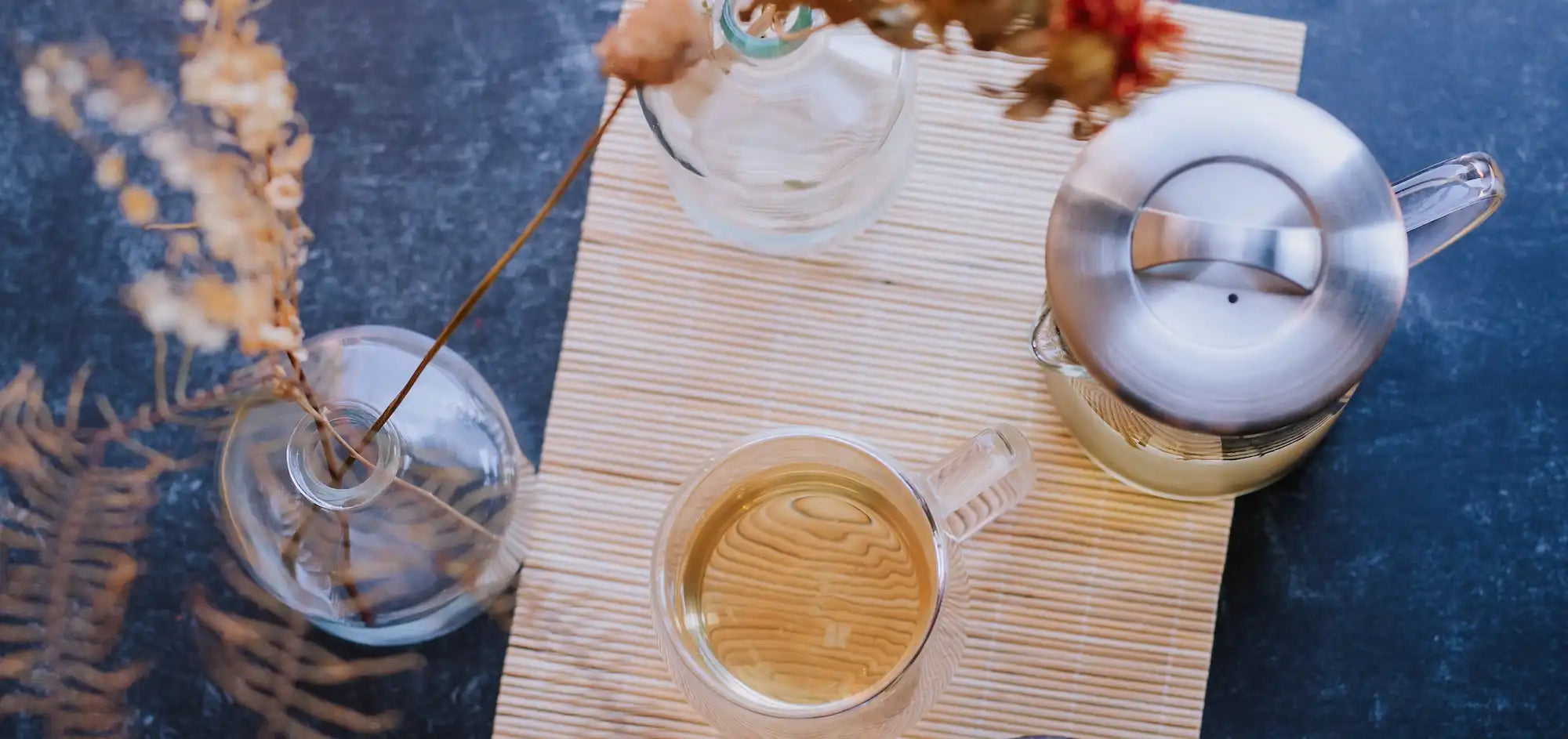 beaker of green tea and clear mug of green tea against a tatami and slate background