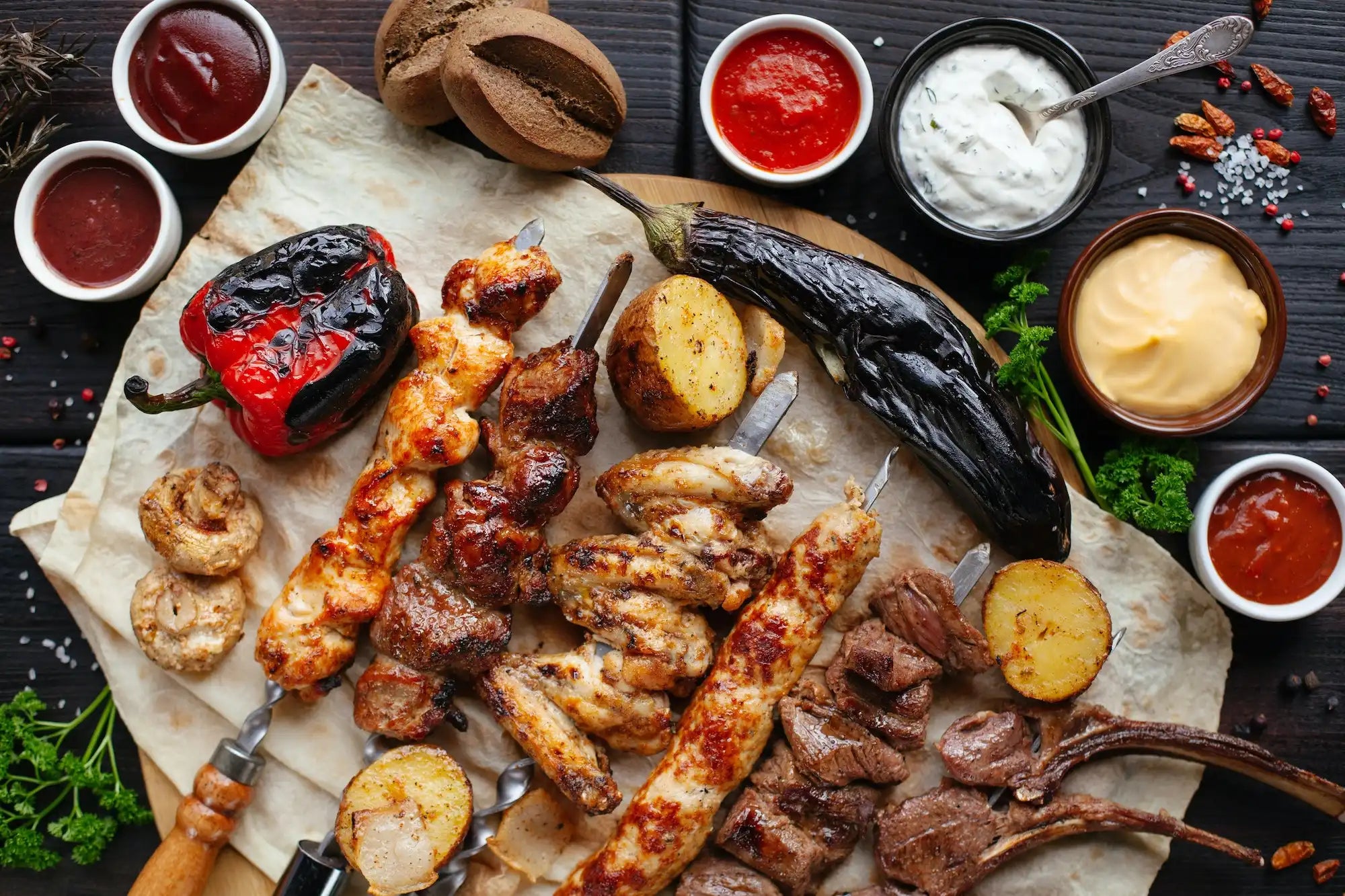 variety of grilled meats and vegetables with side sauces